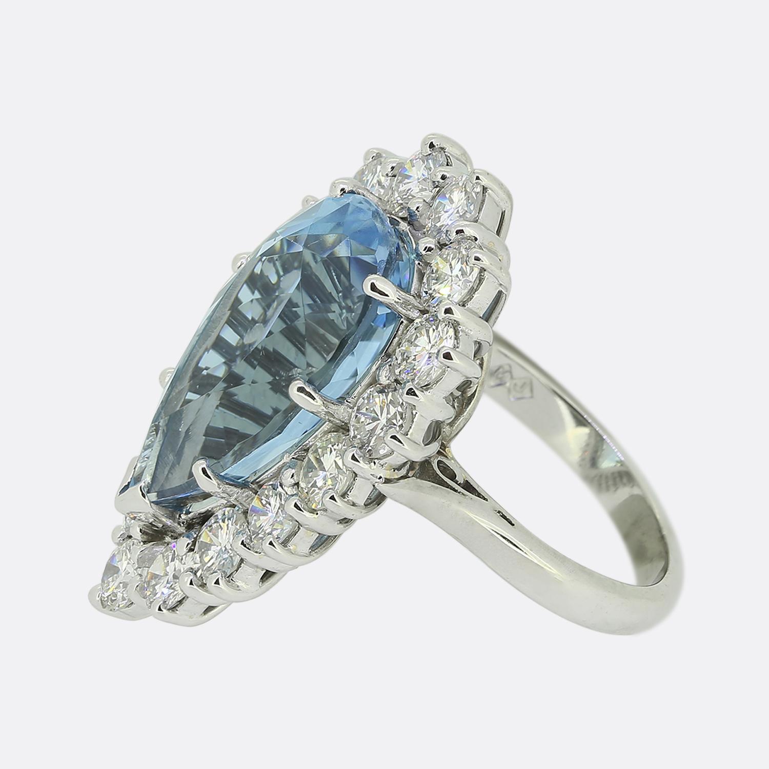 This is a wonderful vintage aquamarine and diamond cluster ring. The ring features a centralised pear shaped aquamarine possessing a beautifully even mid blue tone which is highly complimented by a bright white round brilliant cut diamond set