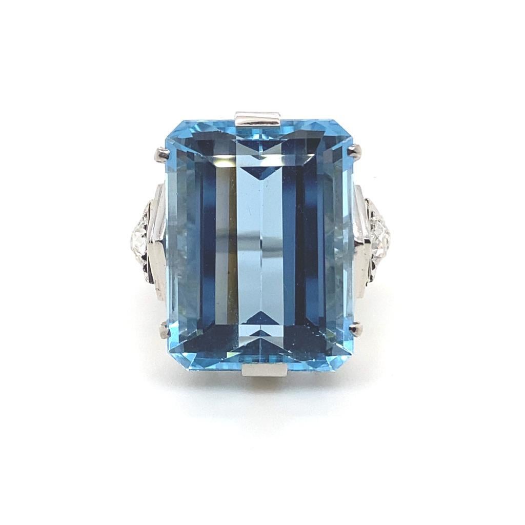 A vintage aquamarine and diamond cocktail ring, circa 1960

This ring is set with an impressive emerald cut aquamarine of 21.03 carats approximately in a plain polished step design leading to tapered shoulders with six old cut diamonds of 1ct