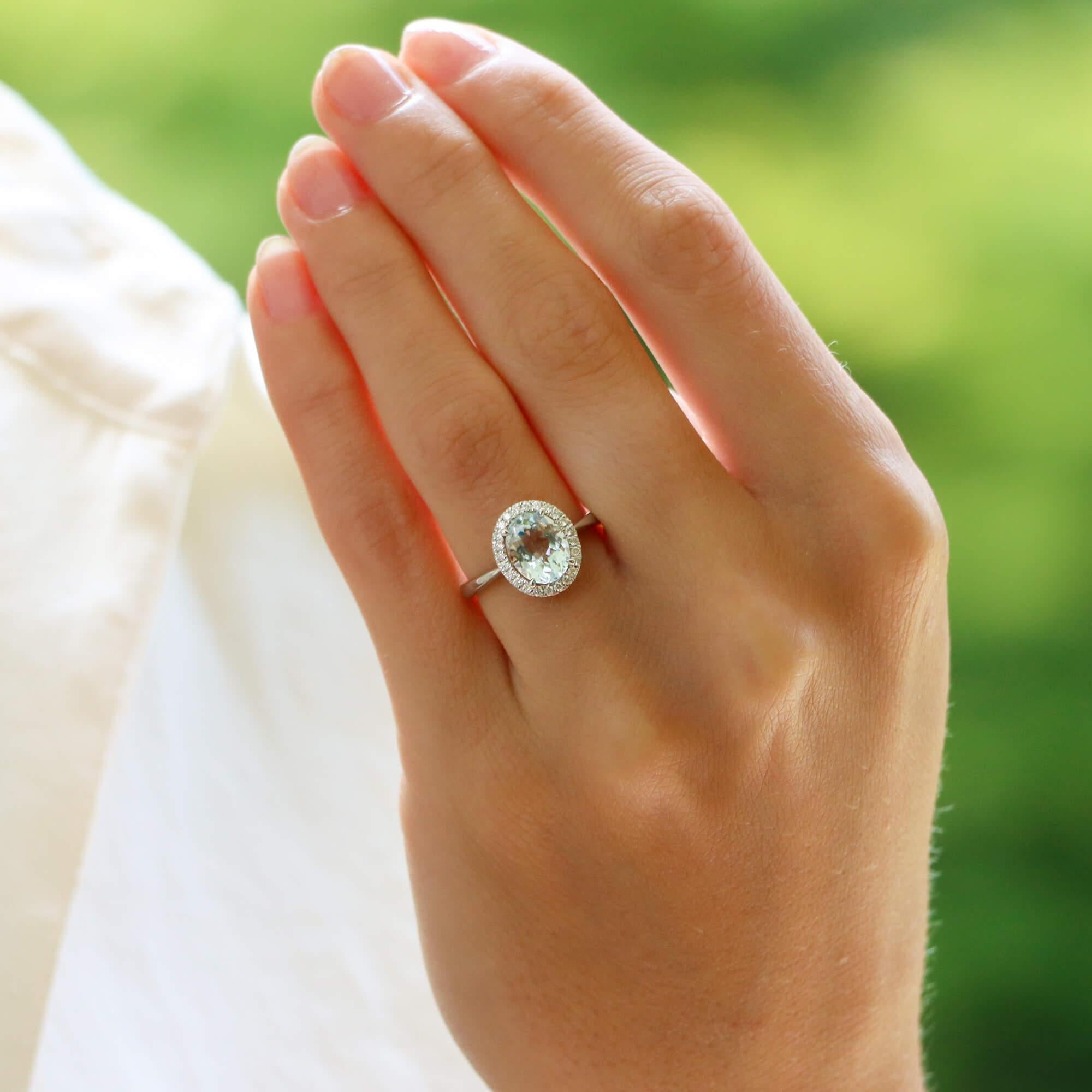 A beautiful vintage aquamarine and diamond oval halo ring set in 18k white gold.

The ring centrally features a beautiful blue coloured oval shaped aquamarine surrounded by a halo of 24 round brilliant-cut diamonds. All of the stones are set in an