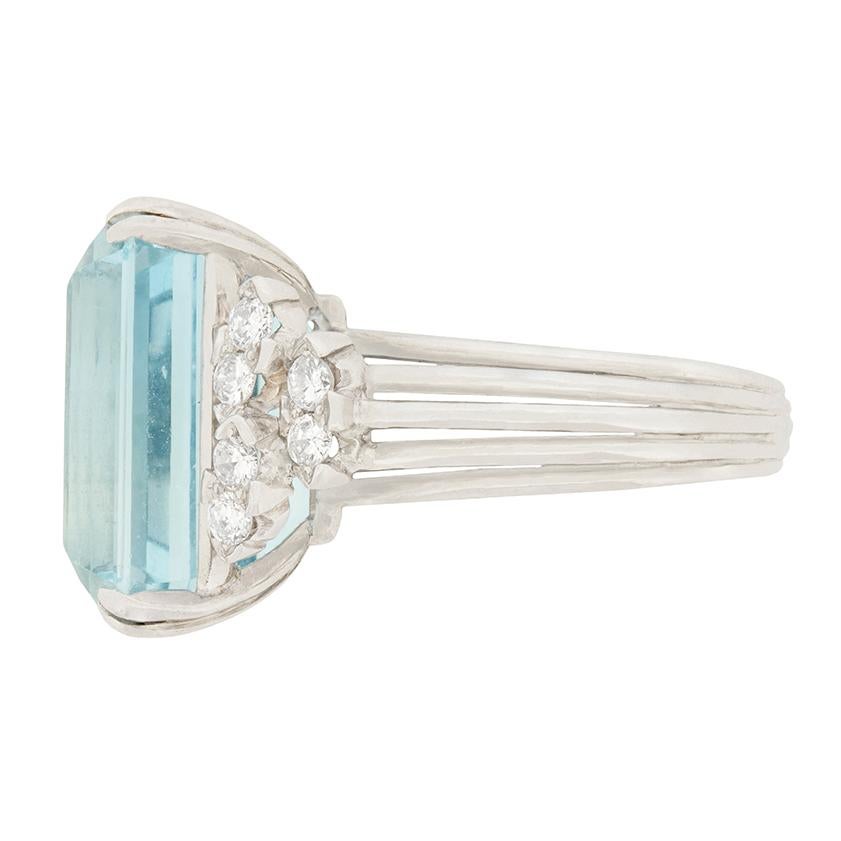 This gorgeous dress ring is there to impress! The centre Emerald cut Aquamarine weighs 18.00 carat and is double claw set. It is a stunning stone, with a lovely pale blue colour and excellent clarity through the stone. The stone is then wonderfully