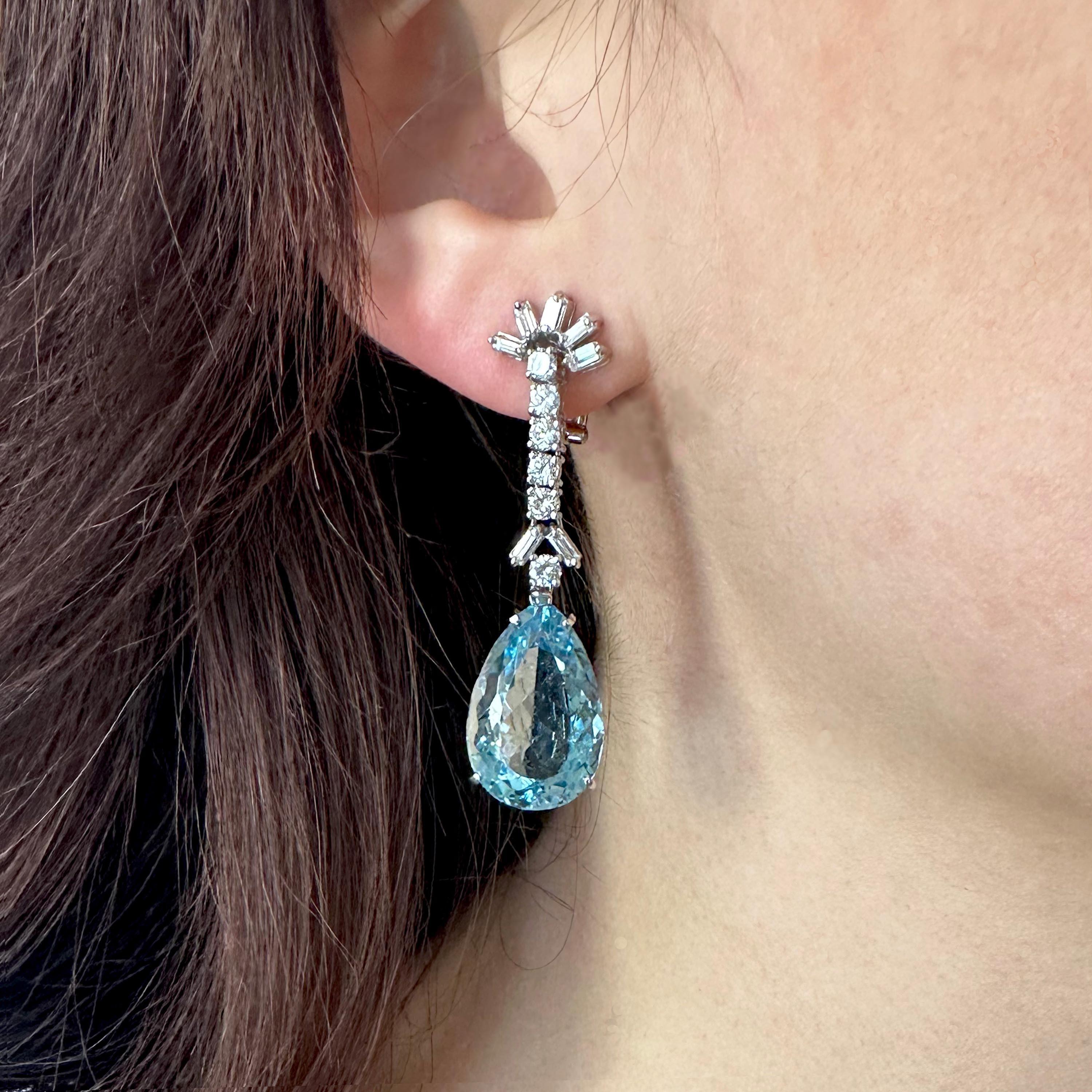 A pair of vintage aquamarine, diamond and white gold drop earrings, with baguette-cut diamond set starburst tops, suspending a row of round brilliant-cut diamonds, in articulated claw settings, with faceted drop shaped aquamarine pendant drops, in