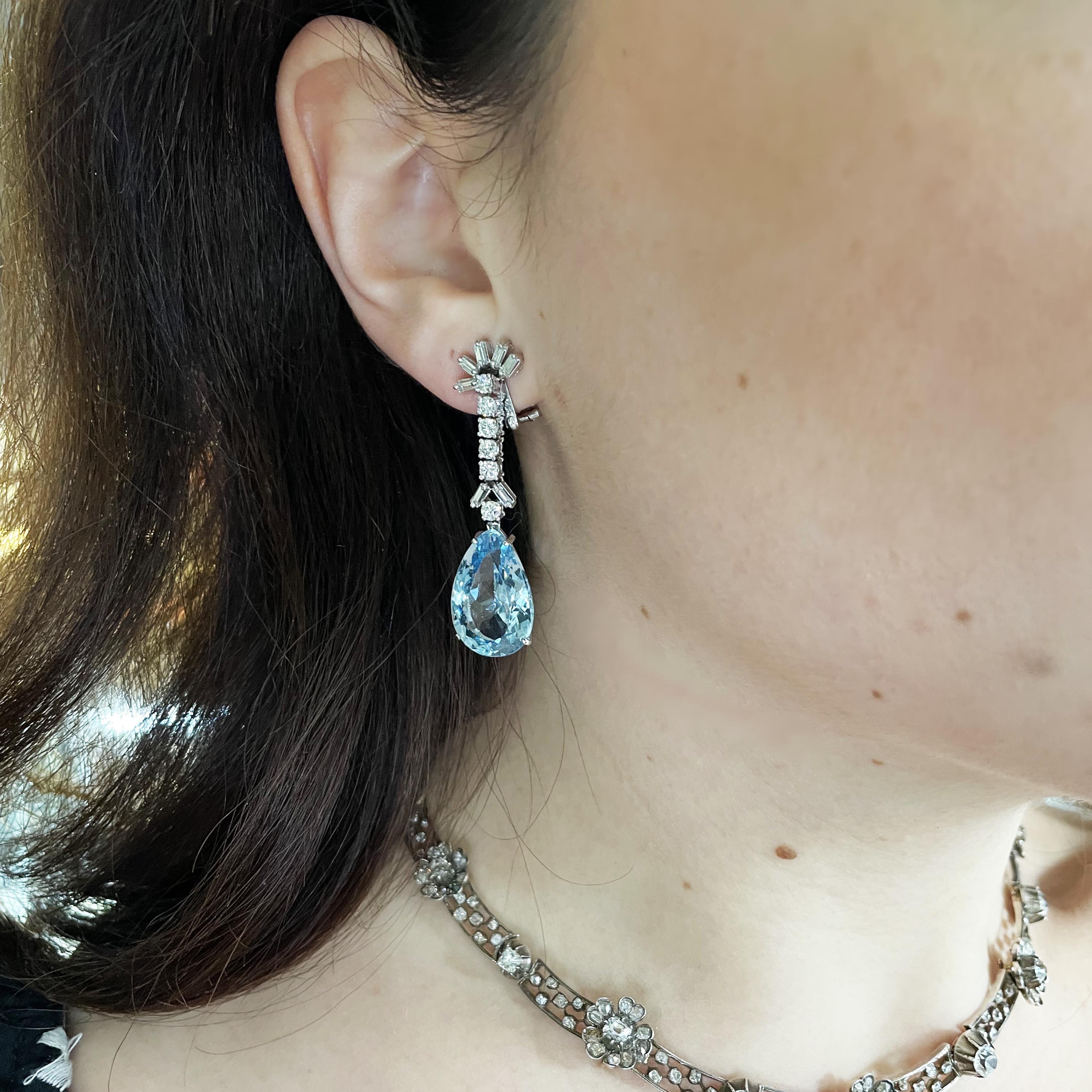 Ein Paar Vintage-Aquamarin-, Diamant- und Weißgold-Tropfenohrringe, mit Diamanten im Baguetteschliff, die eine Reihe runder Brillanten in gegliederten Krallenfassungen tragen, mit facettierten tropfenförmigen Aquamarin-Anhängern in vier