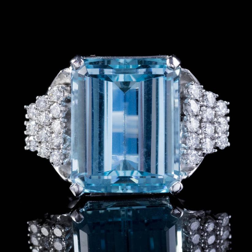 A magnificent vintage cocktail ring made in the Art Deco fashion with a colossal emerald cut aquamarine in the centre, weighing approx. 15ct with a pleasing, deep ocean blue hue.

The aqua is complemented by an audience of twenty-four sparkling