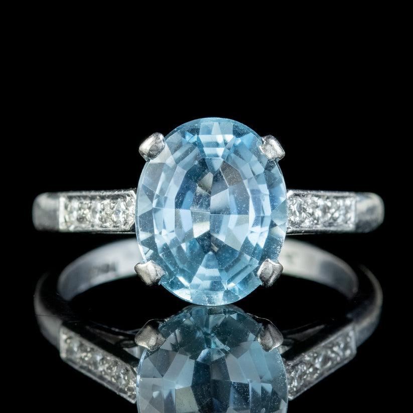 This glamorous vintage ring is bestowed with a gorgeous oval cut aquamarine with glistening facets that mimic light glittering off the surface of a clear blue pool. It weighs approx. 3.8ct and is flanked by three twinkling diamonds chasing down each
