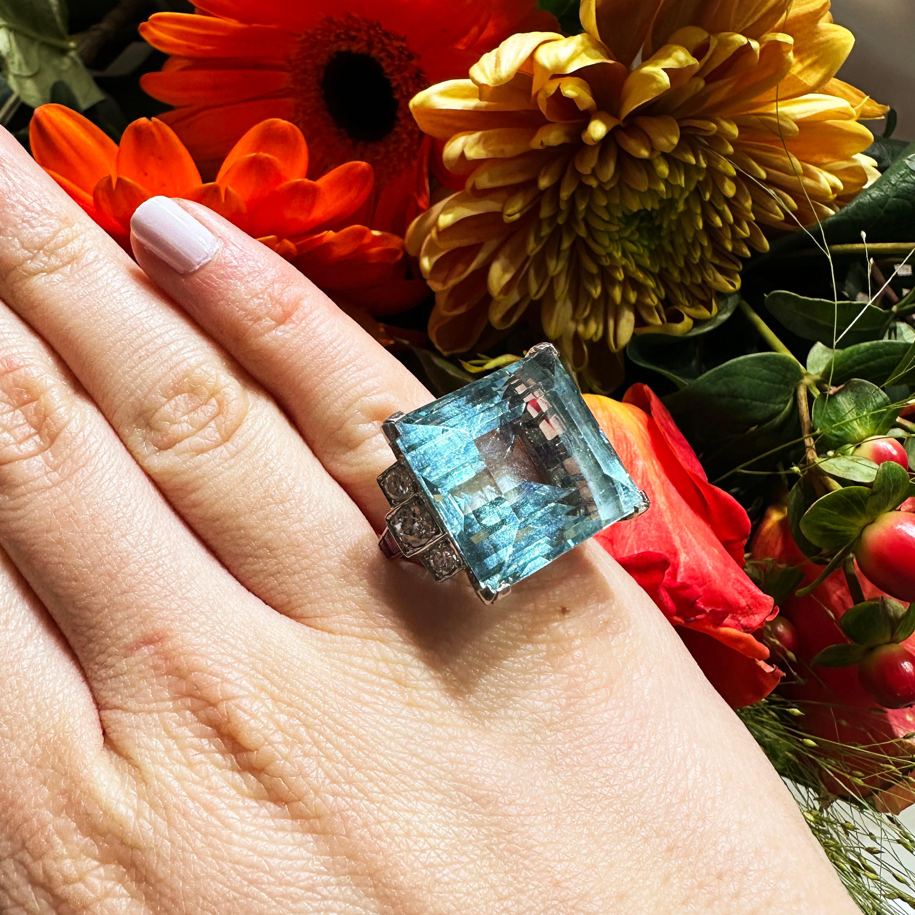 Ein Vintage-Aquamarin-, Diamant-, Rubin- und Platinring, besetzt mit einem rechteckigen Aquamarin im Stufenschliff, mit einem Gewicht von ca. 36,16 Karat, in einer Vier-Krallen-Fassung, mit drei Diamanten in Kornfassungen in jeder Schulter, die