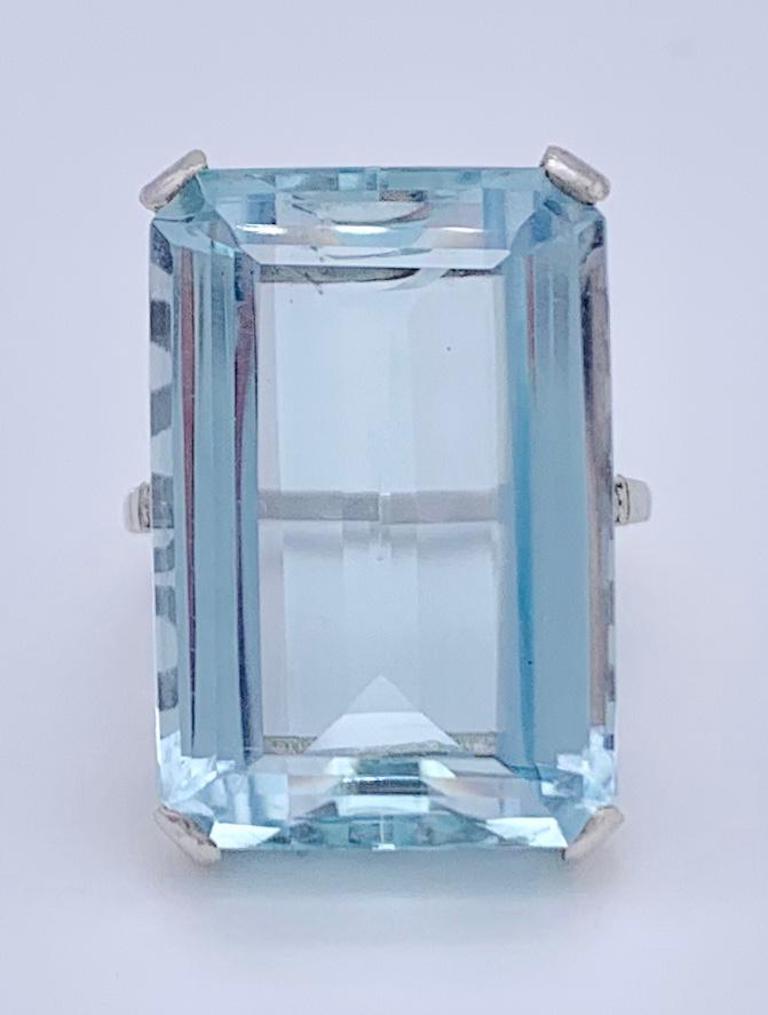 This elegant cocktail ring has been set with a rectangular aquamarin in stepcut. It is mounted in a 14 kt whitegold shank . The ring shoulders have been set with small diamonds.
The aquamarine has an established weight of 26,49ct. It is a light