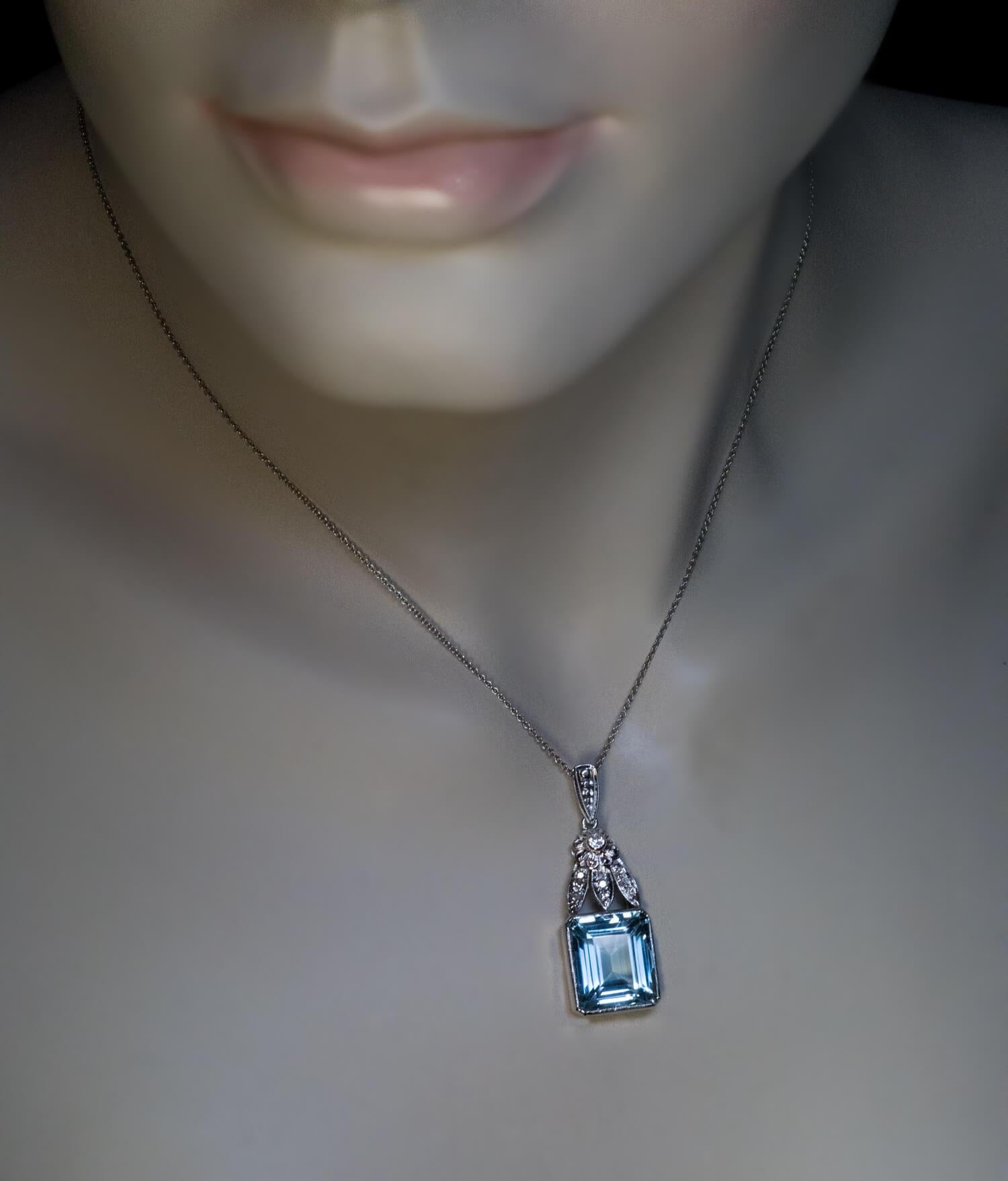 Circa 1950s

The 18K white gold necklace features a bezel-set emerald cut aquamarine of a cool blue color surmounted by three leaves and a flower head embellished with small diamonds.

The aquamarine measures 13.4 x 11.5 x 8.1 mm and is