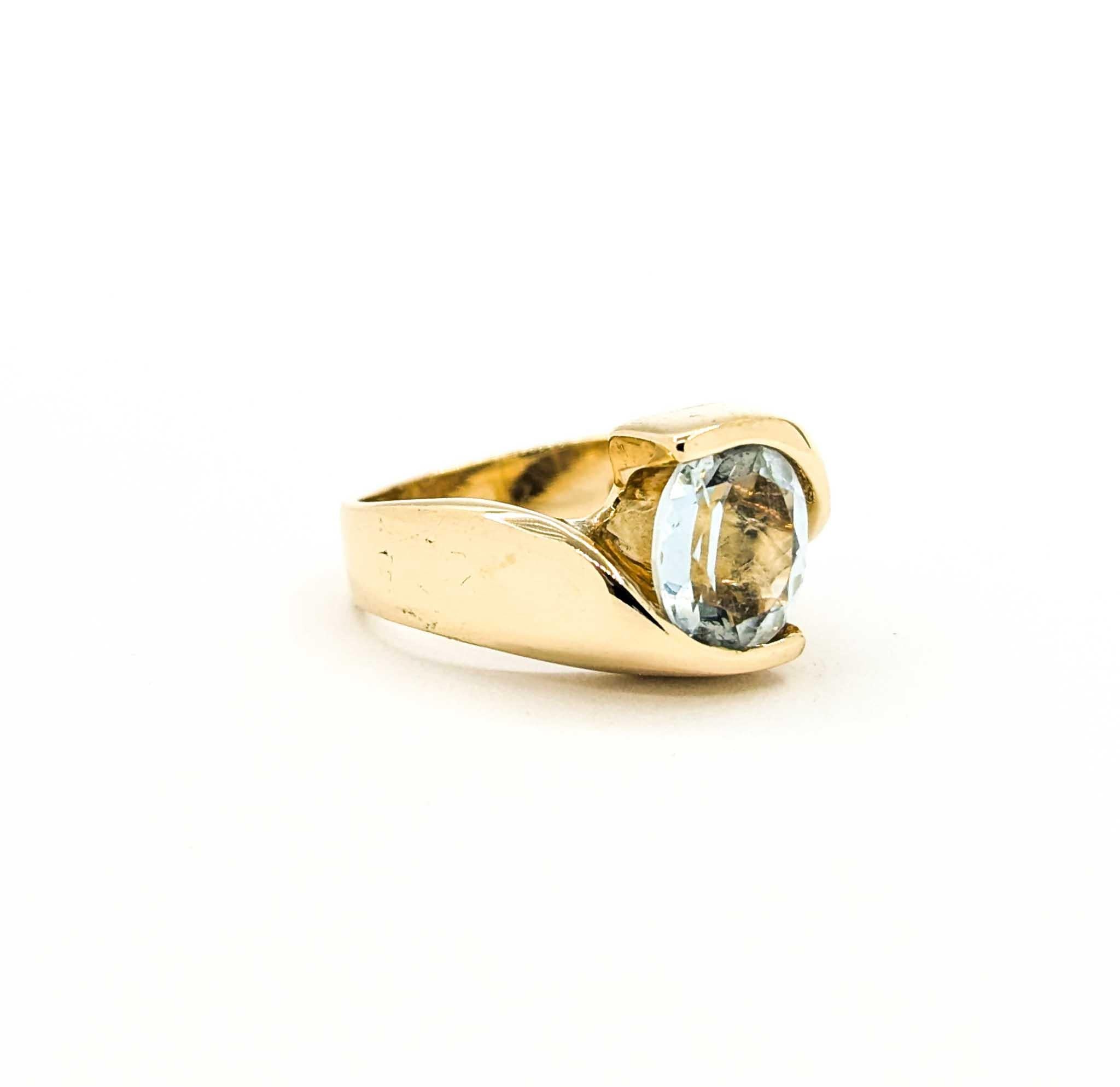This vintage ring showcases a sparkling 1.75 carat oval-cut aquamarine, elegantly secured in a modern bypass-style setting. The soft, icy blue hue of the aquamarine is highlighted by the warm glow of 14k yellow gold, giving the ring a sleek yet