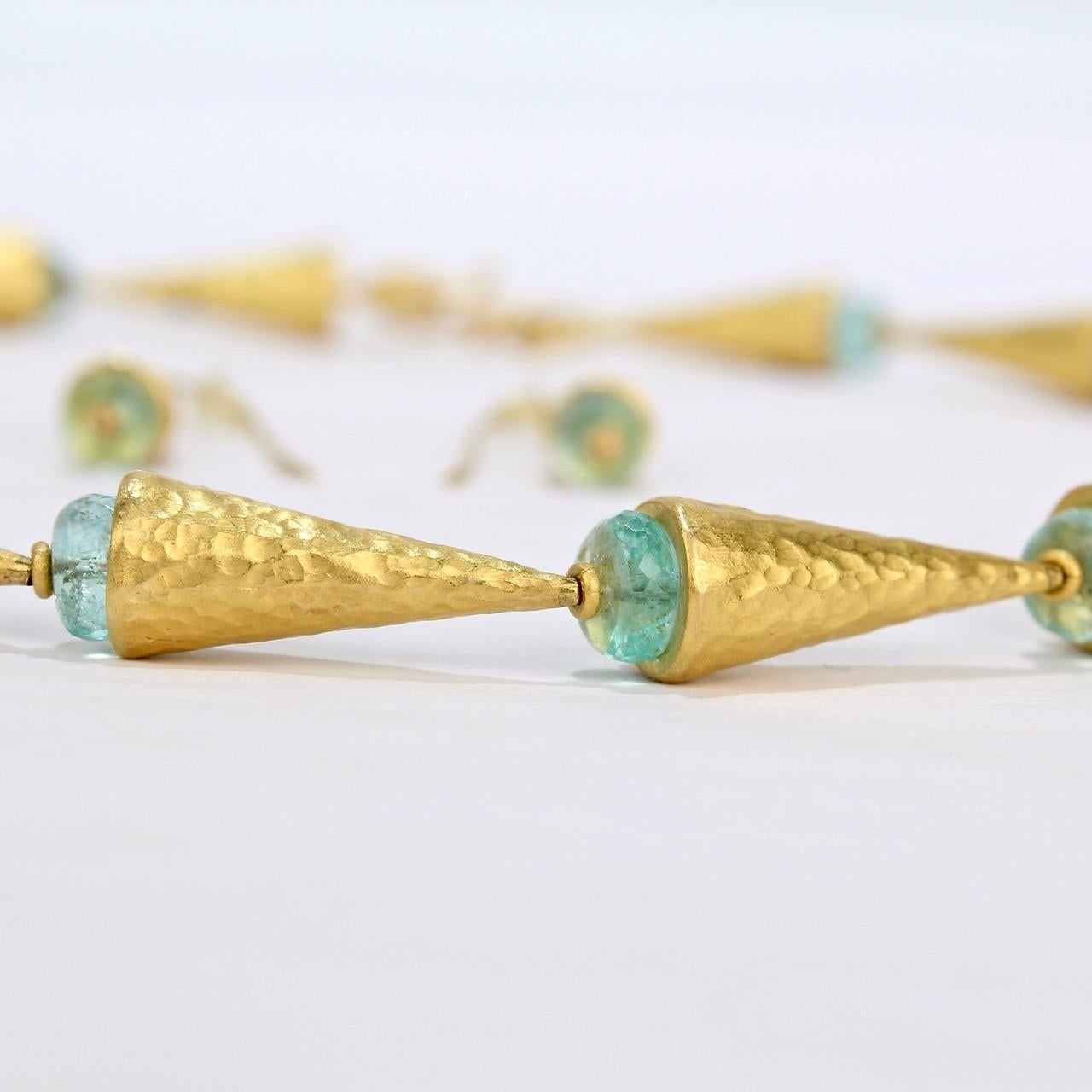 An Ara necklace and earring set in 24K gold and emerald beads.

With a wonderful Egyptian Revival or Ancient Mediterranean feel, both the necklace and earrings consist of cone-shaped hand-hammered beads offset by faceted rondelle-cut emerald beads.
