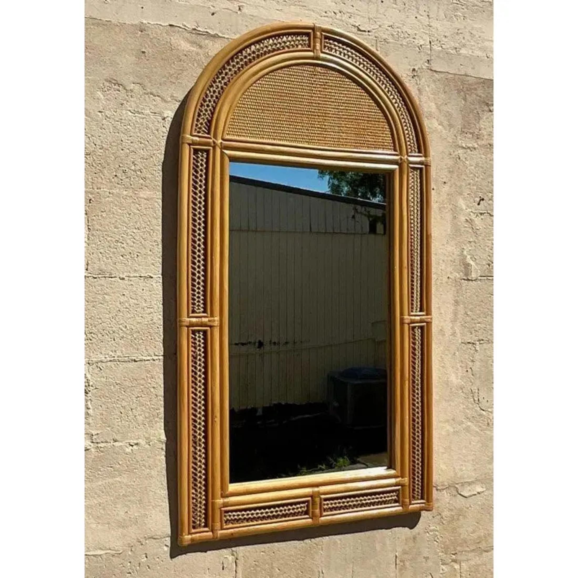 A fabulous vintage Coastal wall mirror. Chic arched rattan with a woven band along the edge. Acquired from a Palm Beach estate