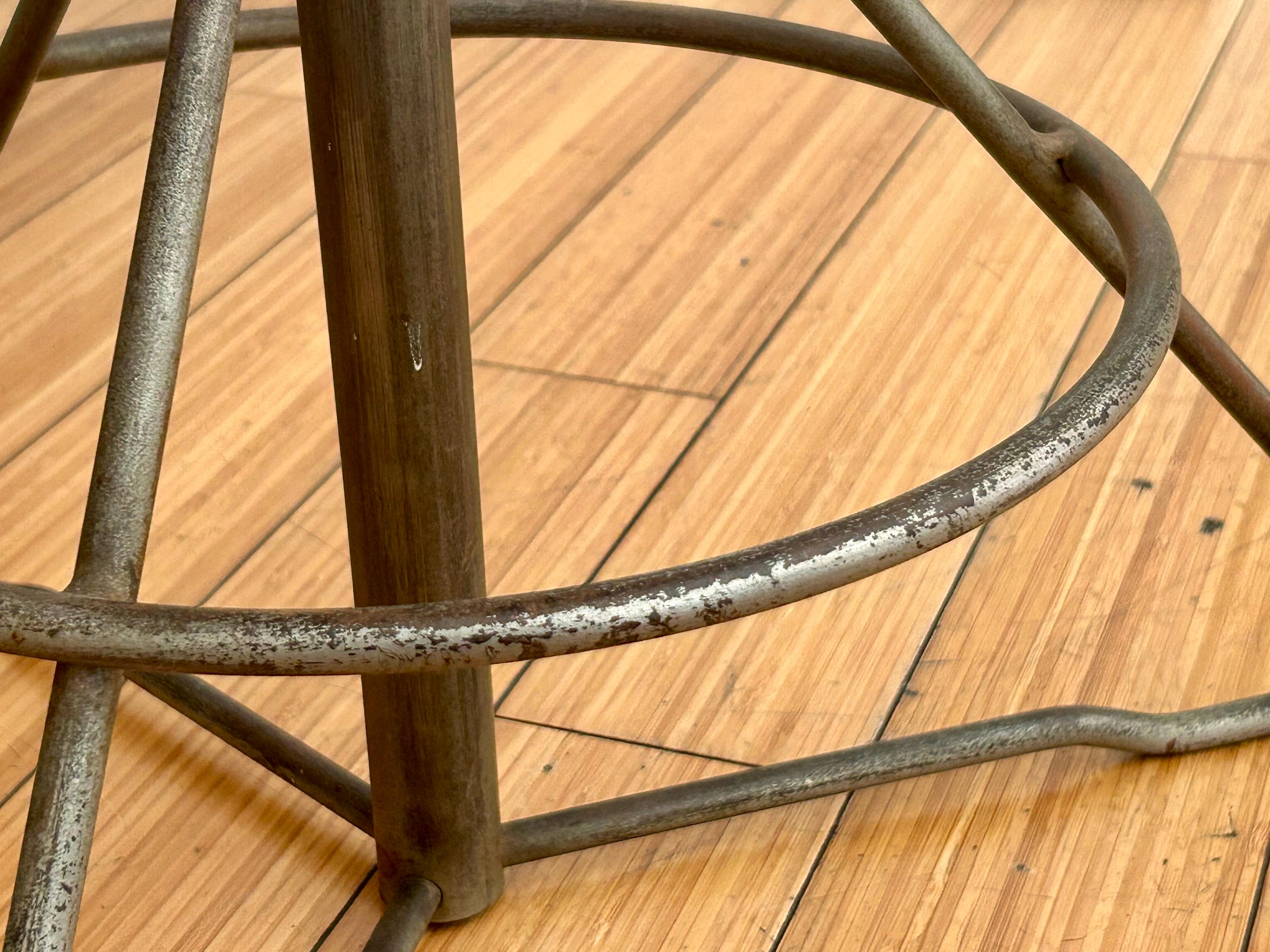 Originelles modernistisches Design.
Platte / Sitz aus rundem Birkenholz, Untergestell aus Architekturstahl mit Originalschrauben. 
Das Holz wurde vor ein paar Jahren leicht aufgefrischt.
Der Sockel ist in originalem Vintage-Zustand mit alters- und