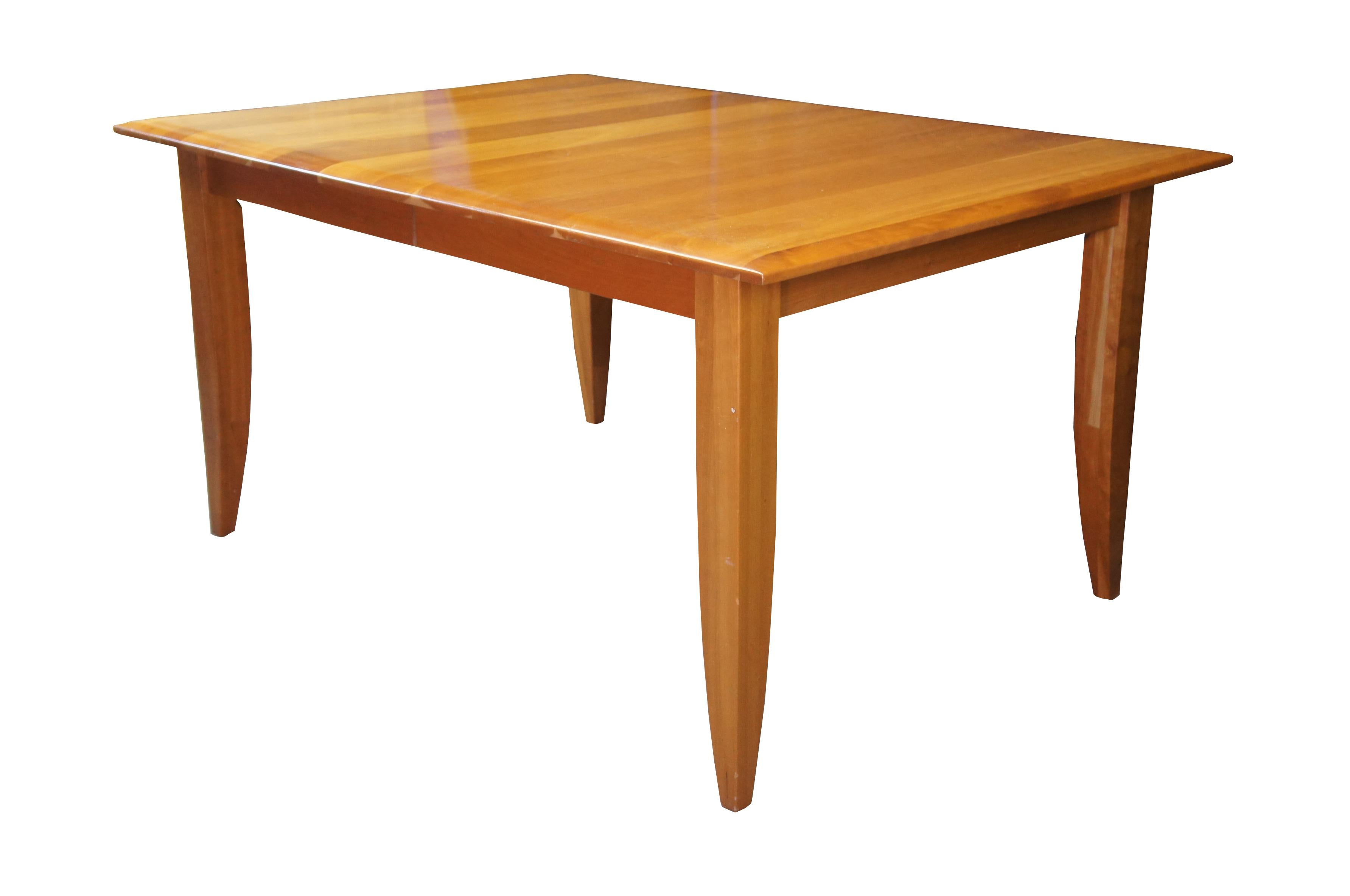 A lovely Arhaus Italian Cherry farmhouse Shaker or Amish style dining table. Features a large rectangular top with planks running perpendicular to the table top. The table is supported by square legs that taper towards the feet. Includes two leaves