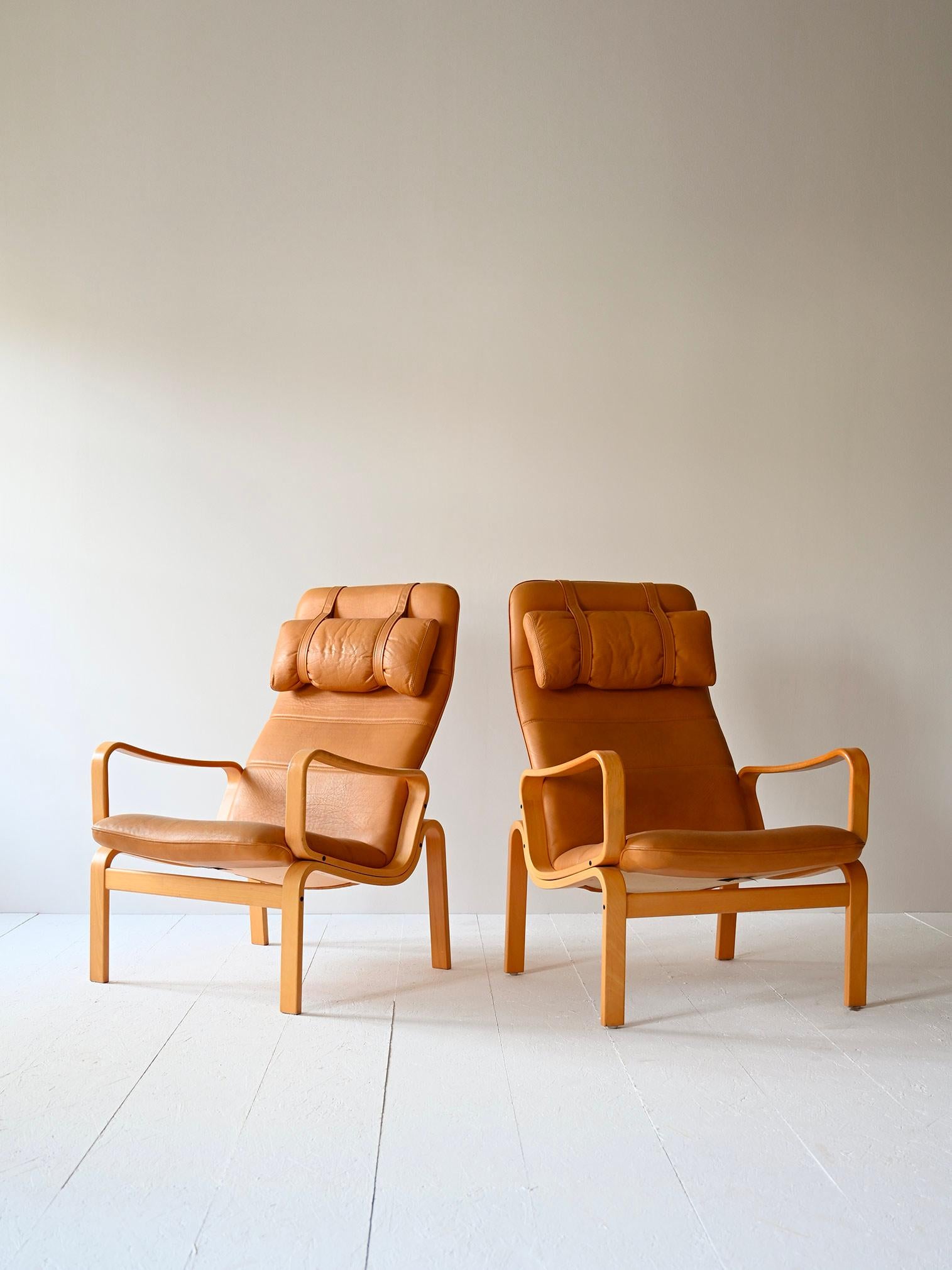 Pair of vintage 1980s chairs of Scandinavian manufacture.

These elegant and comfortable armchairs consist of a curved birch wood frame and an upholstered seat covered in beige leather. The sinuous shapes hark back to the organic design of