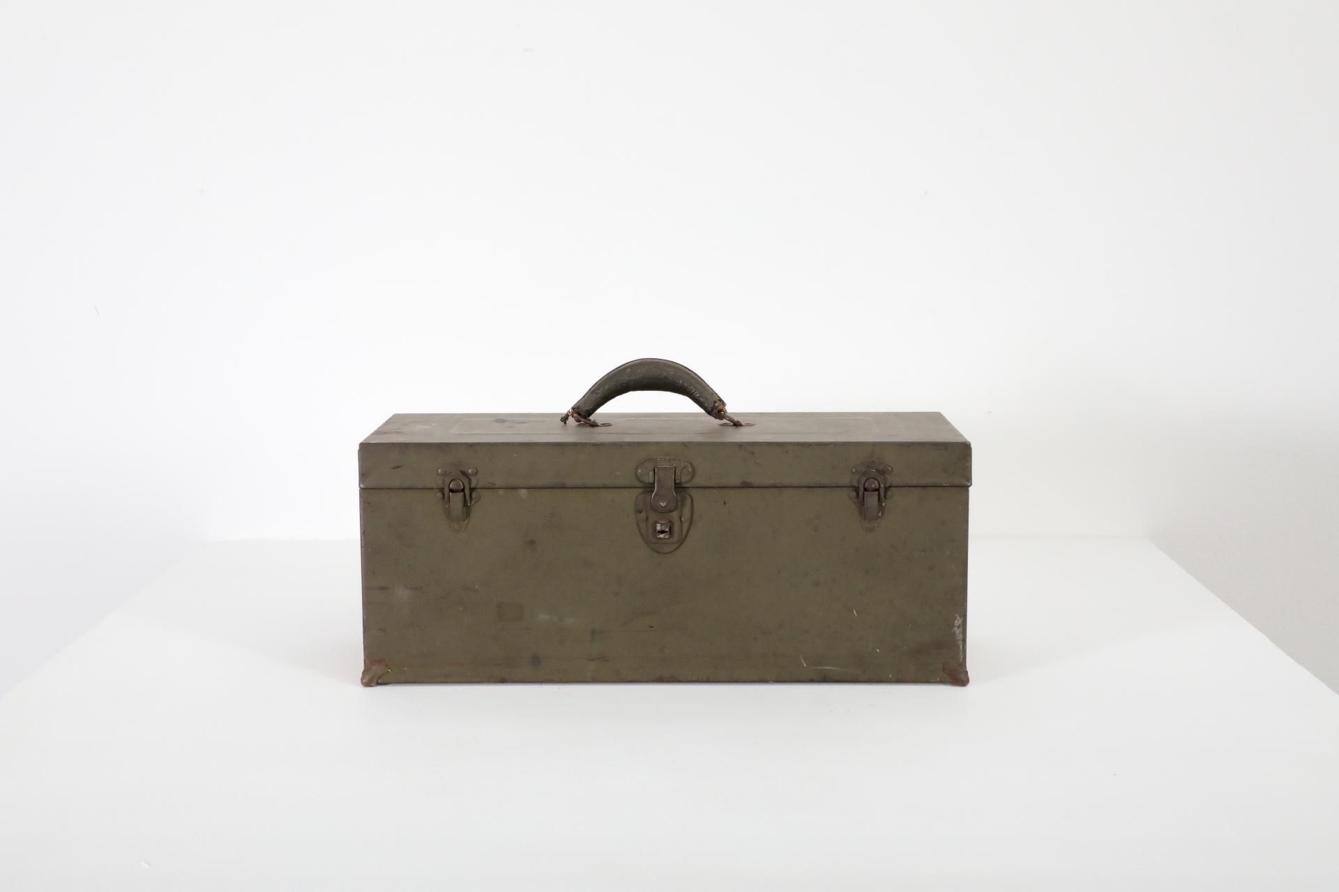 Vintage green metal tool box with leather handle. In original condition with visible wear, including enamel loss, discoloration and scratches. Wear is consistent with its age and use. Other toolboxes listed separately.
