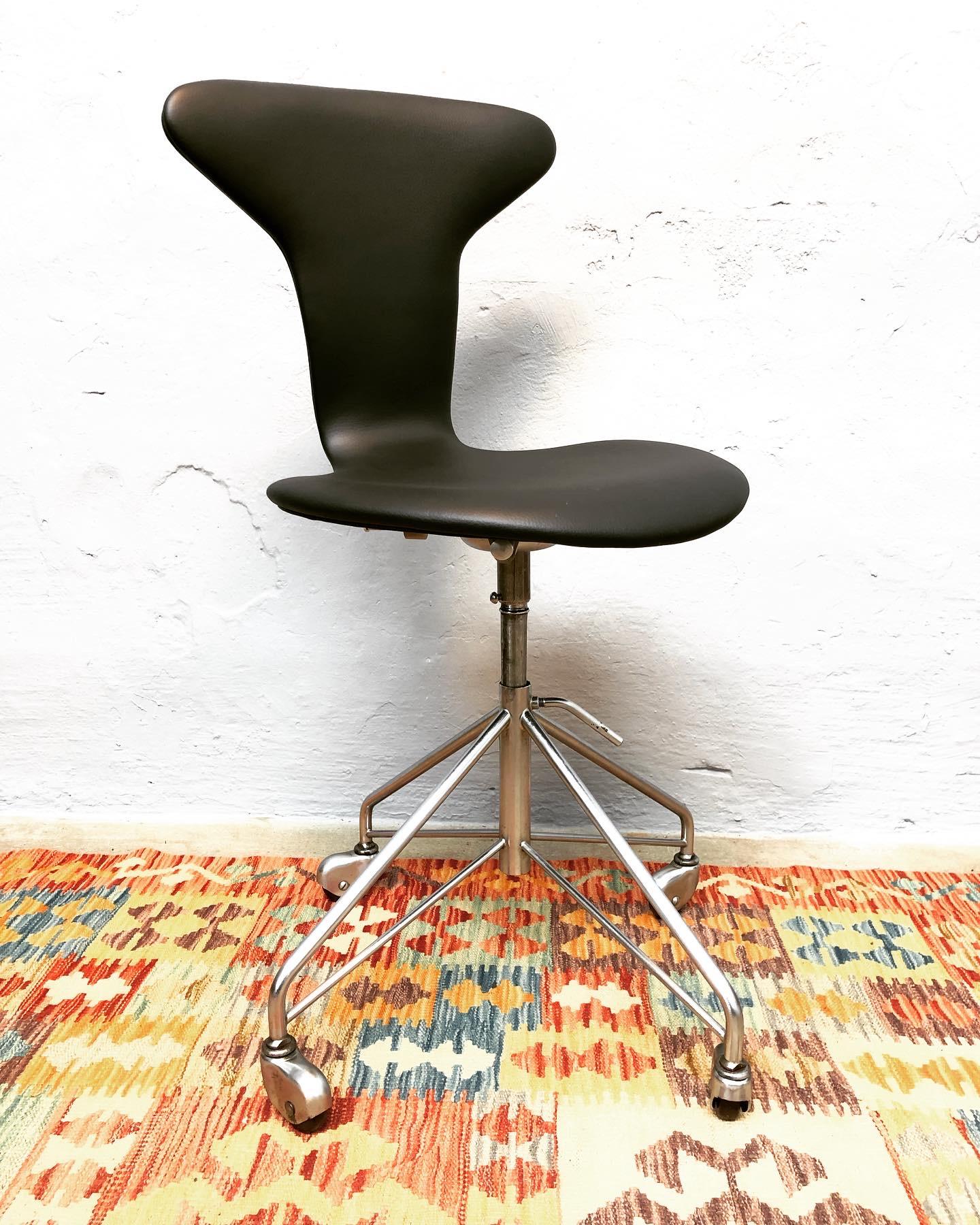 Vintage Arne Jacobsen Munkegaard office swivel stool model 3115 from 1964 with its original label. 
This stool is in great condition and has been recently refurbished professionally in black semi anilin leather.
With all its original parts, wheels