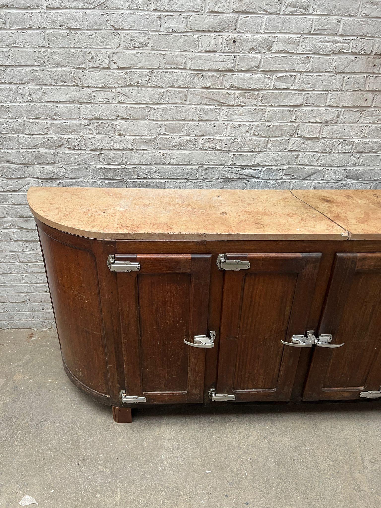 This is a stunning vintage arrière-bar with a natural marble top and a solid wooden body. Featuring six front-opening compartments with original nickel-plated latches, this piece was originally used as a professional back bar cabinet. Its interior