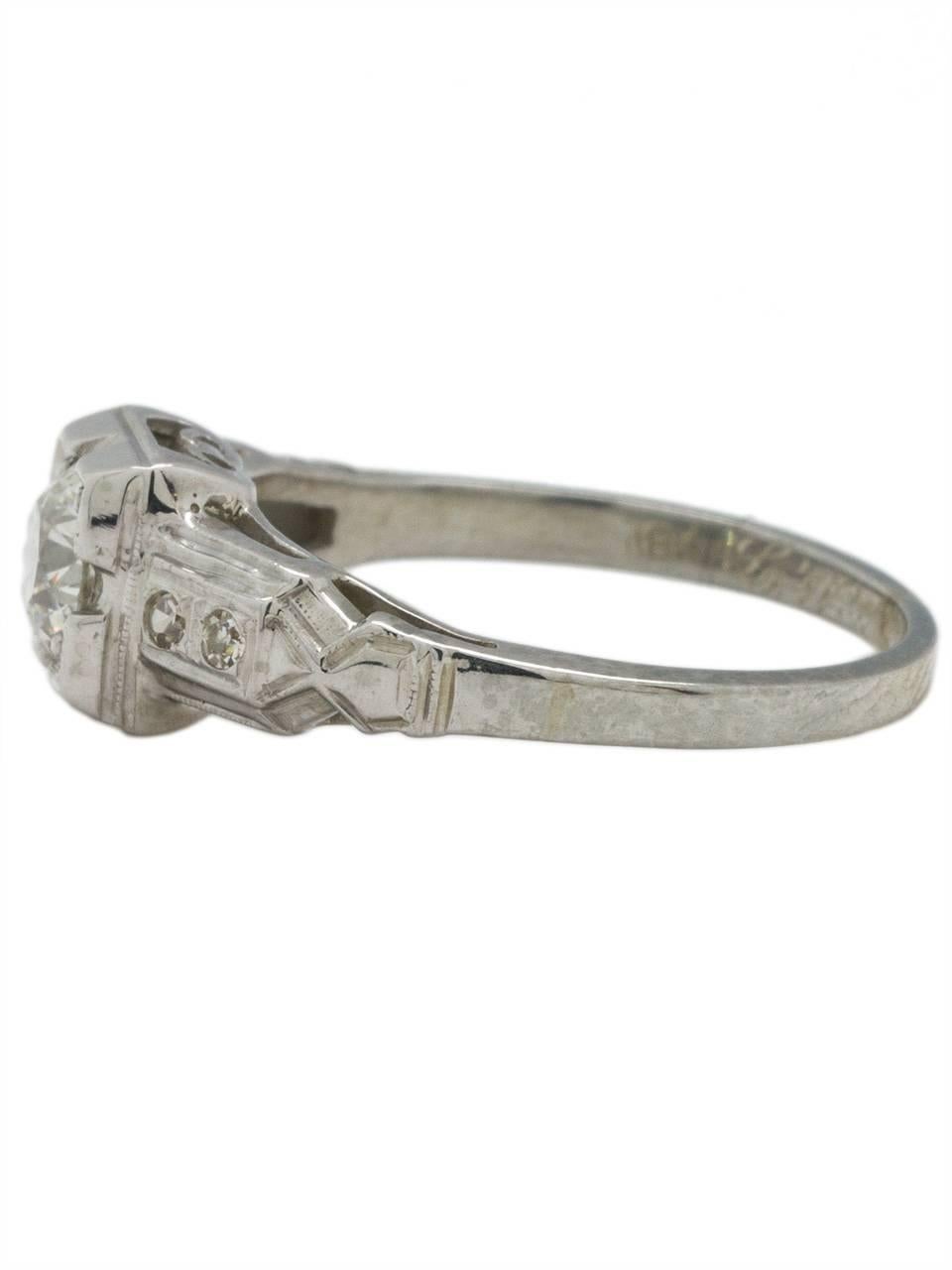 This gorgeous antique 18K white gold engagement ring is a classic example of Art Deco style- bold architectural lines with feminine details such as the open galleries with scroll motif and milgrain detail throughout. The lively .50ct Old European