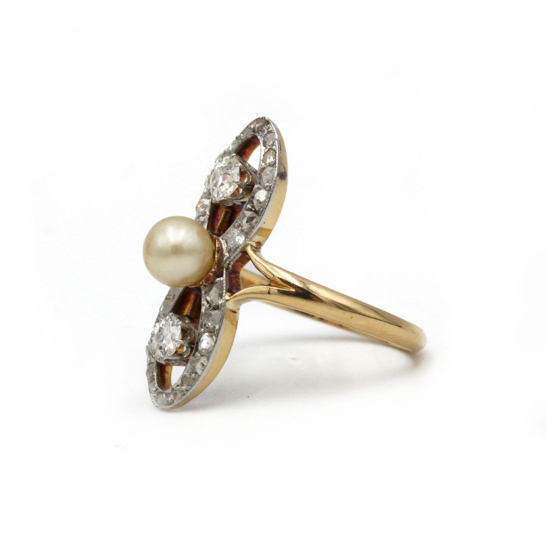 This elegant Art Deco ring, crafted in rich 18K yellow gold (750‰), presents a poised vertical “figure-8” motif set with a lustrous natural pearl at its center. At the top and bottom sit two old-mine–cut diamonds (approx. 0.20 ct each), their