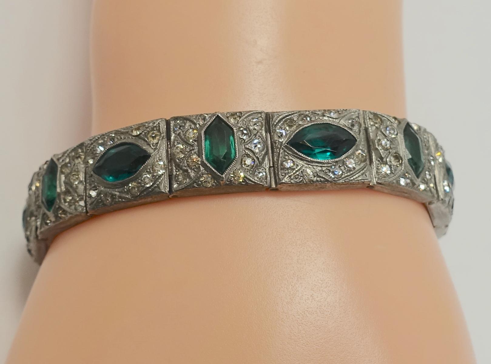 This vintage Art Deco 1920s bracelet features green and clear crystals in a rhodium silver tone setting.  In excellent condition, this bracelet measures 7” x 7/16” with a slide in clasp.