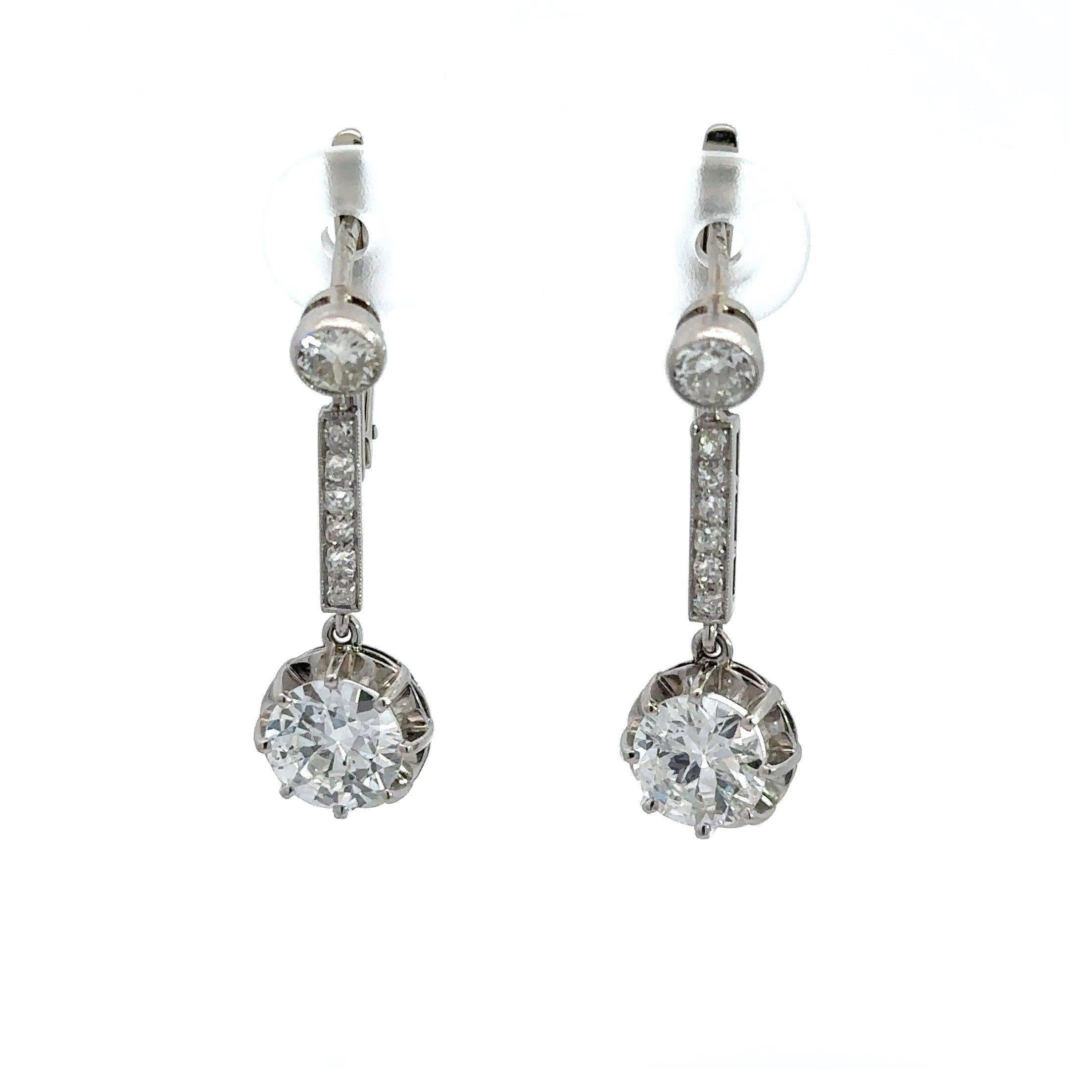 These antique 2.4CT diamond platinum Art Deco earrings were crafted in France c. 1925. The earrings feature two old European-cut diamonds, approximately  1.72CT, with fourteen old European-cut accent diamonds, approximately .68CT. The diamonds are