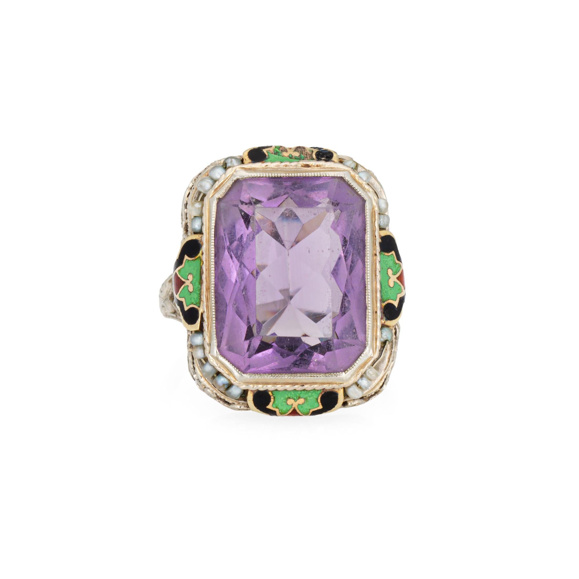 Anillo de cóctel vintage de amatista de la época Art Déco (circa años 30) elaborado en oro blanco de 14 quilates.

La amatista facetada de talla cuadrada mide 15 mm x 12 mm. Pequeñas perlas naturales de 1 mm engarzadas en la montura. El esmalte