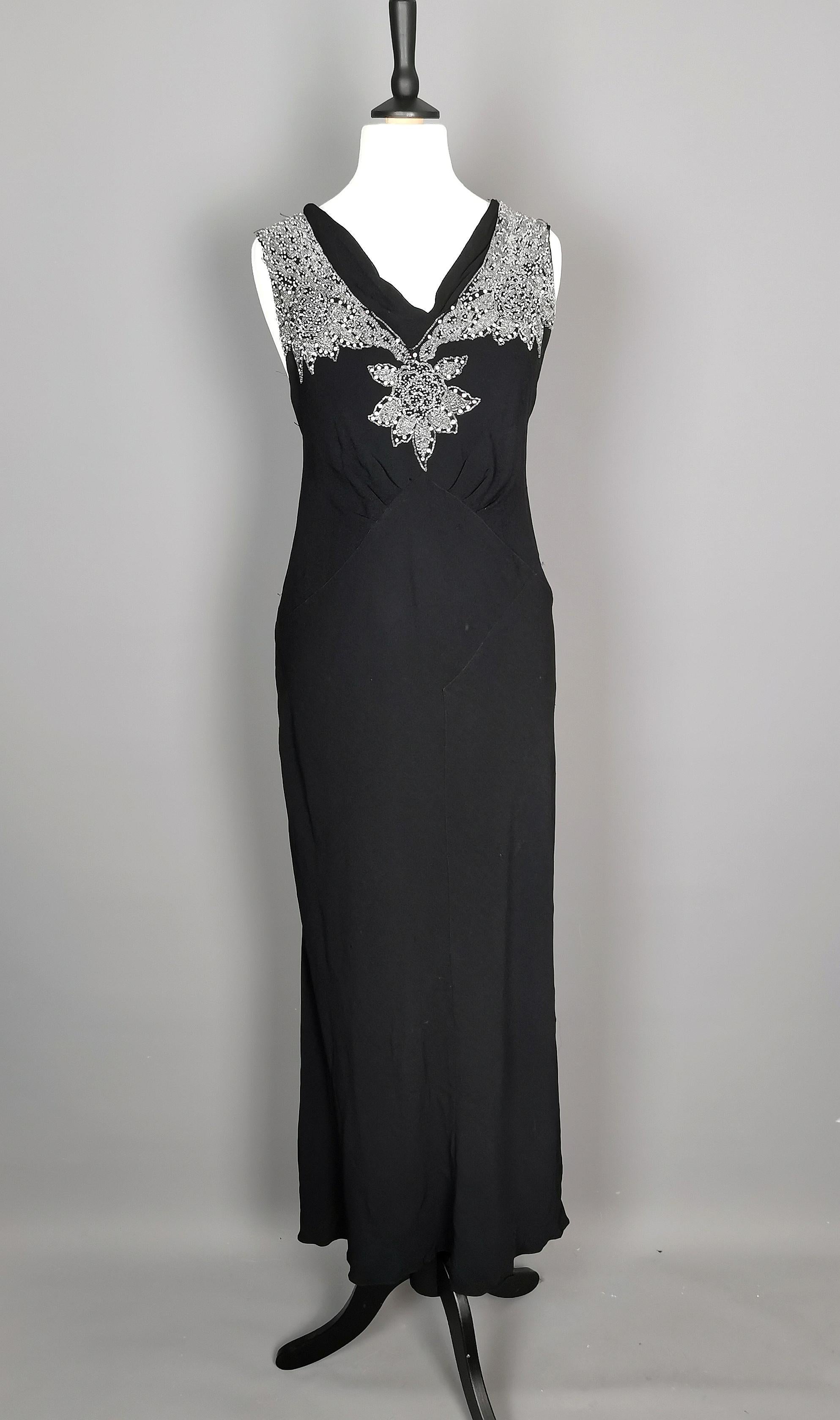 A gorgeous vintage 1930's Black beaded dress.

A slinky black crepe rayon dress with a v neck, cinched in at the waist with a beautiful bias cut and heavily beaded shoulders and mid.

It has a figure hugging silhouette with some stretch to the
