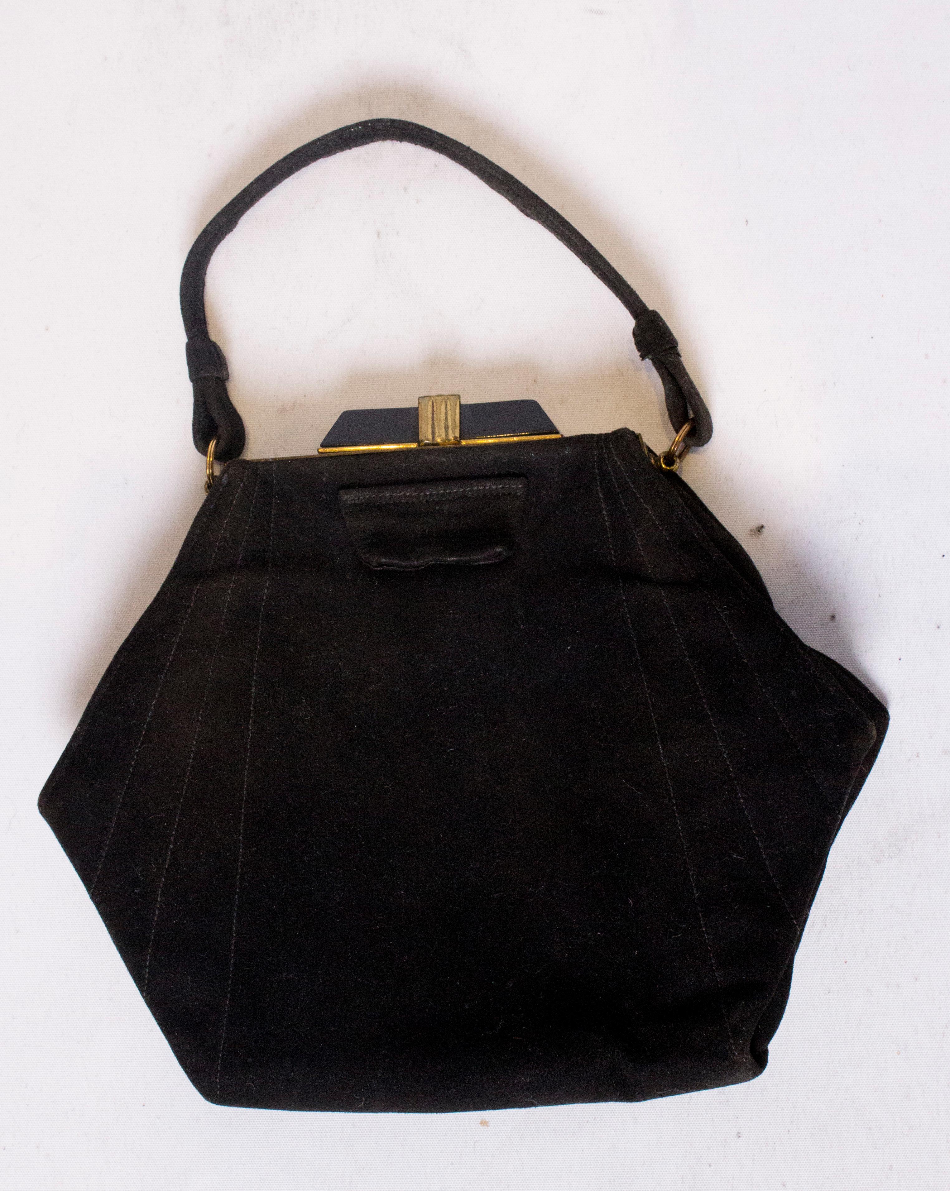 A chic hexaganol shape Art Deco handbag in black suede. The bag has a decorative art deco clasp and is lined in fabric with one internal pouch pocket and integrated purse.
Measurements: width 8'', height 7'', depth 2''.