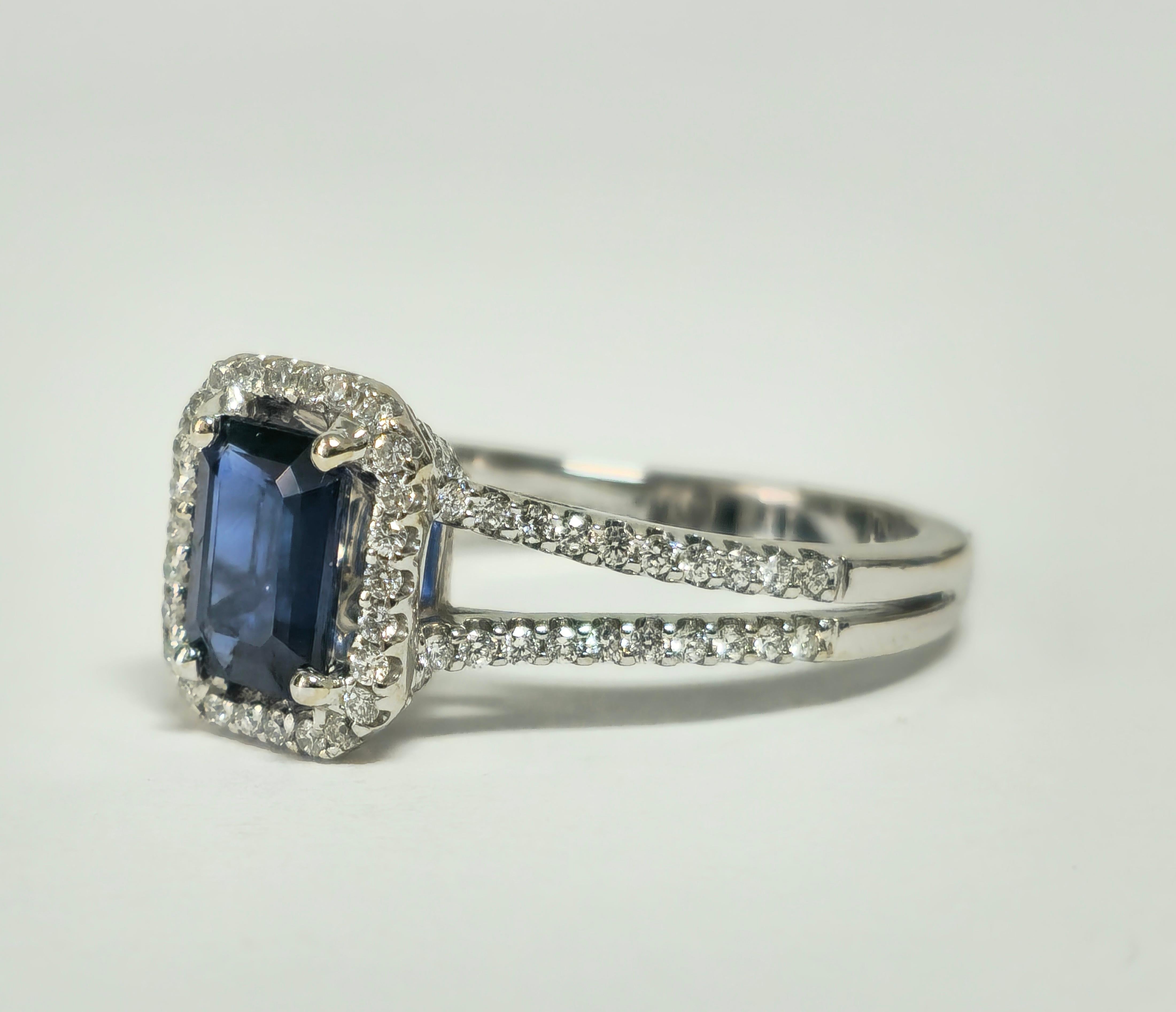 Gönnen Sie sich Raffinesse mit unserem blauen Saphir- und Diamantring im Vintage Art Deco-Stil, der aus luxuriösem 18-karätigem Weißgold gefertigt ist. Mit einem atemberaubenden blauen Saphir von 1,00 Karat im Smaragdschliff, der in Zacken gefasst