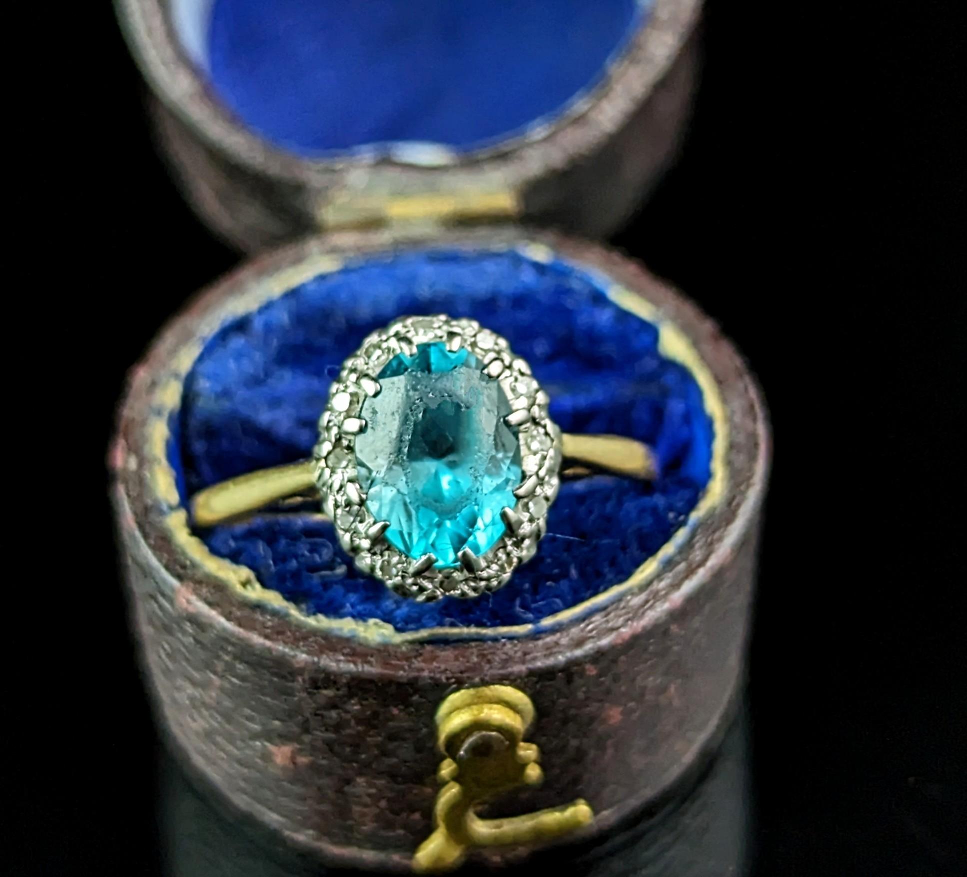 A pretty vintage Art Deco era Blue Zircon and Diamond cluster ring.

A rich 18ct yellow gold band with a vibrant blue zircon to the centre, oval cut and surrounded by a halo of small single cut diamonds in a cool silver setting to enhance the