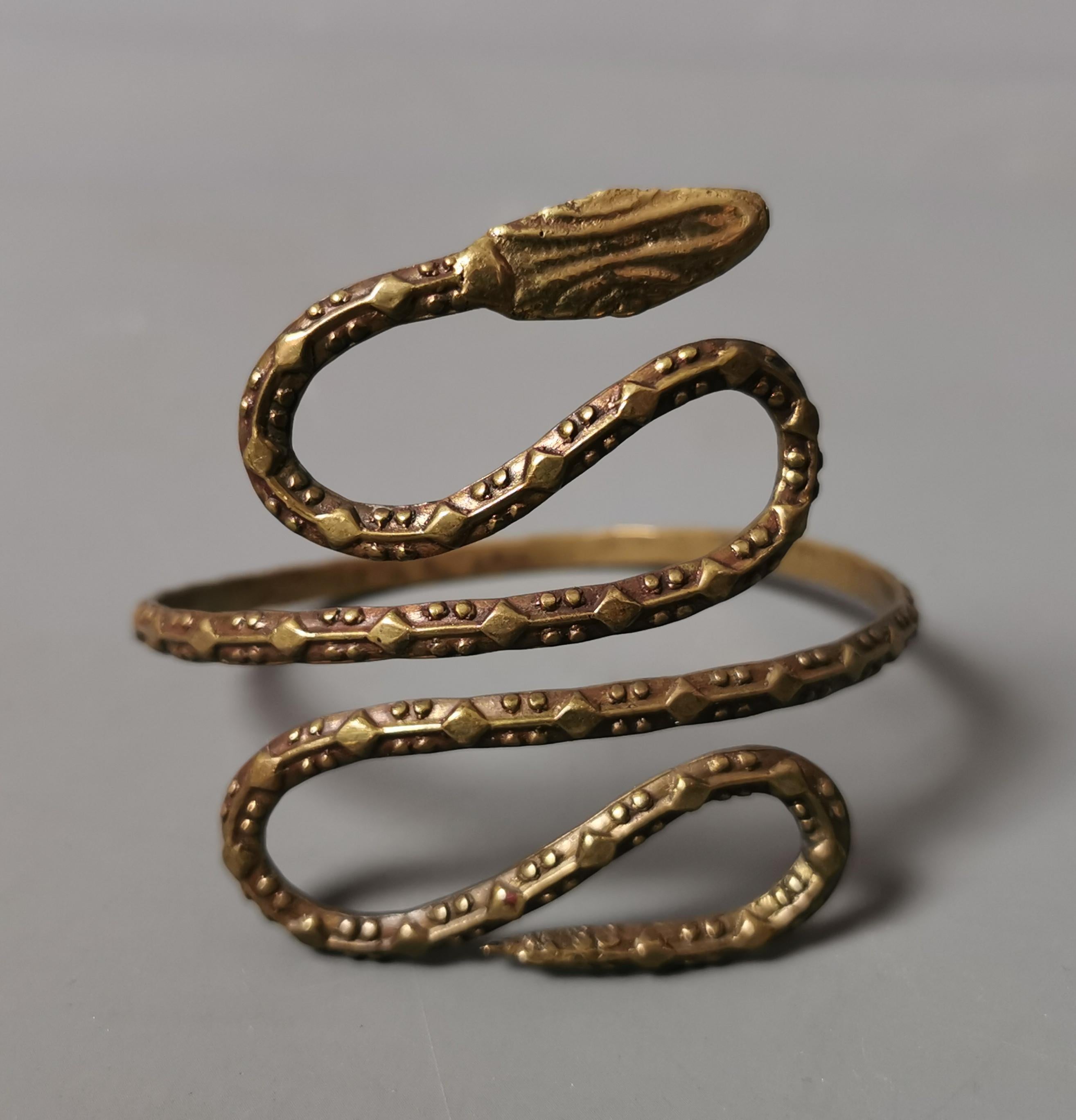 A rare vintage Art Deco, 1920s snake arm cuff bangle.

Elements of the Egyptian revival style are evident in this piece and it is designed to be worn on the upper arm.

The bangle is made from hammered brass and the snake is textured all around the