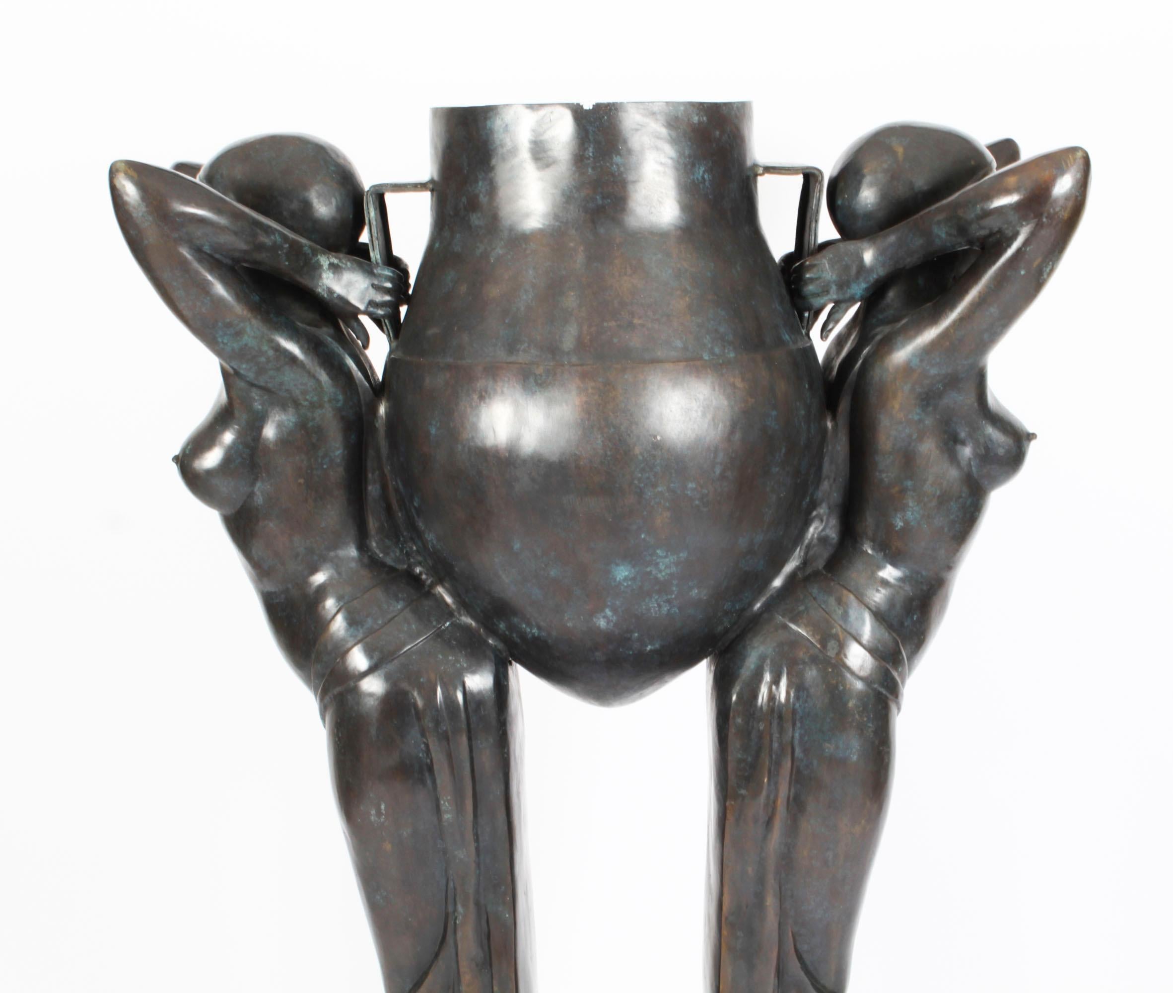 Questo è un vero e proprio  splendido jardiniere monumentale a grandezza naturale raffigurante una coppia di figure femminili seminude che indossano gonne fluenti e che reggono un'urna etrusca.

In stile Art Déco senza tempo, realizzato in bronzo
