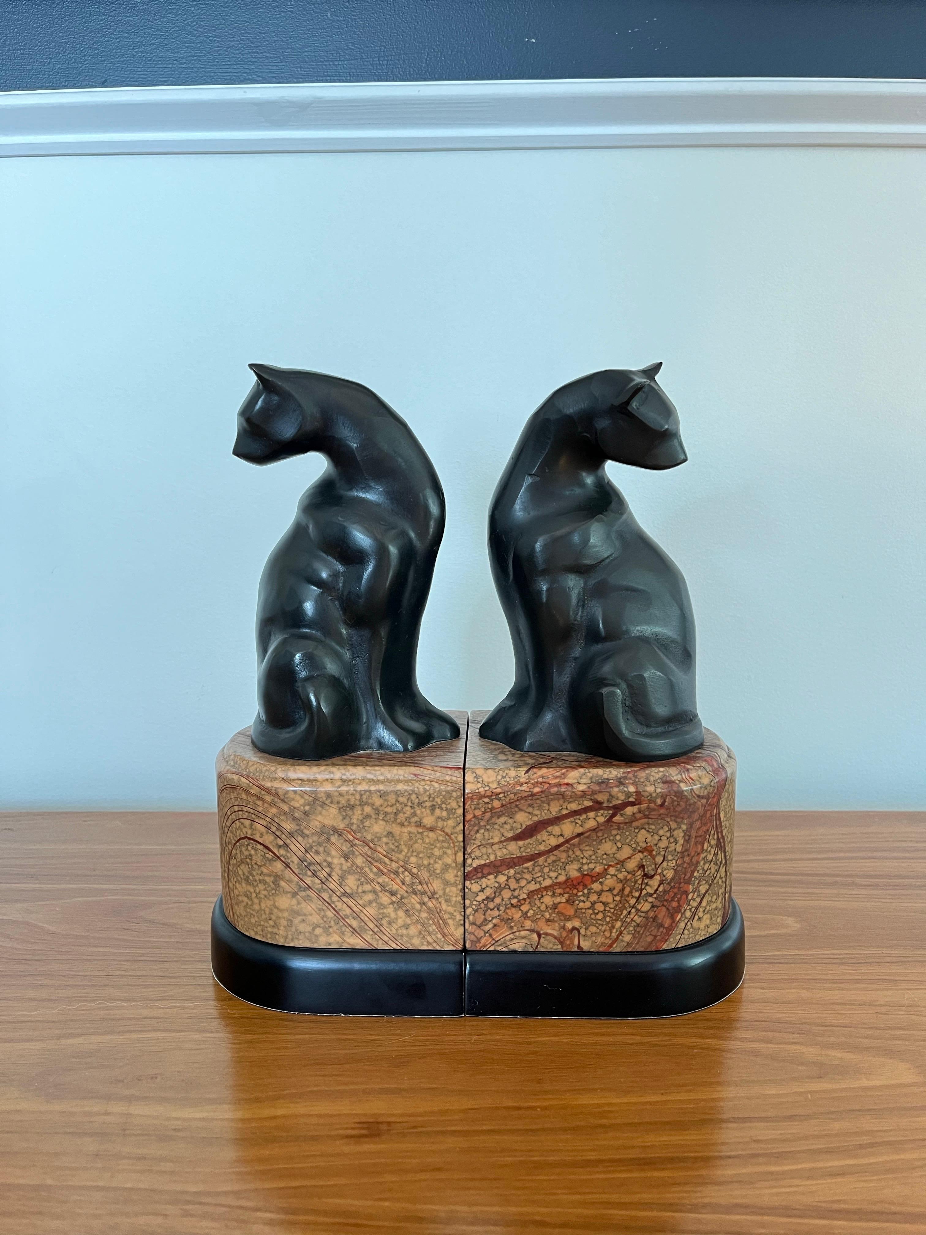 Beautiful art deco patinated model of sitting cats bookends in the manner of Jacques (Nam) Lehmann. Wonderful visual exemplifying art deco style. Opposing cat figure sit perched on faux marble plinth bases that complete the period styling.