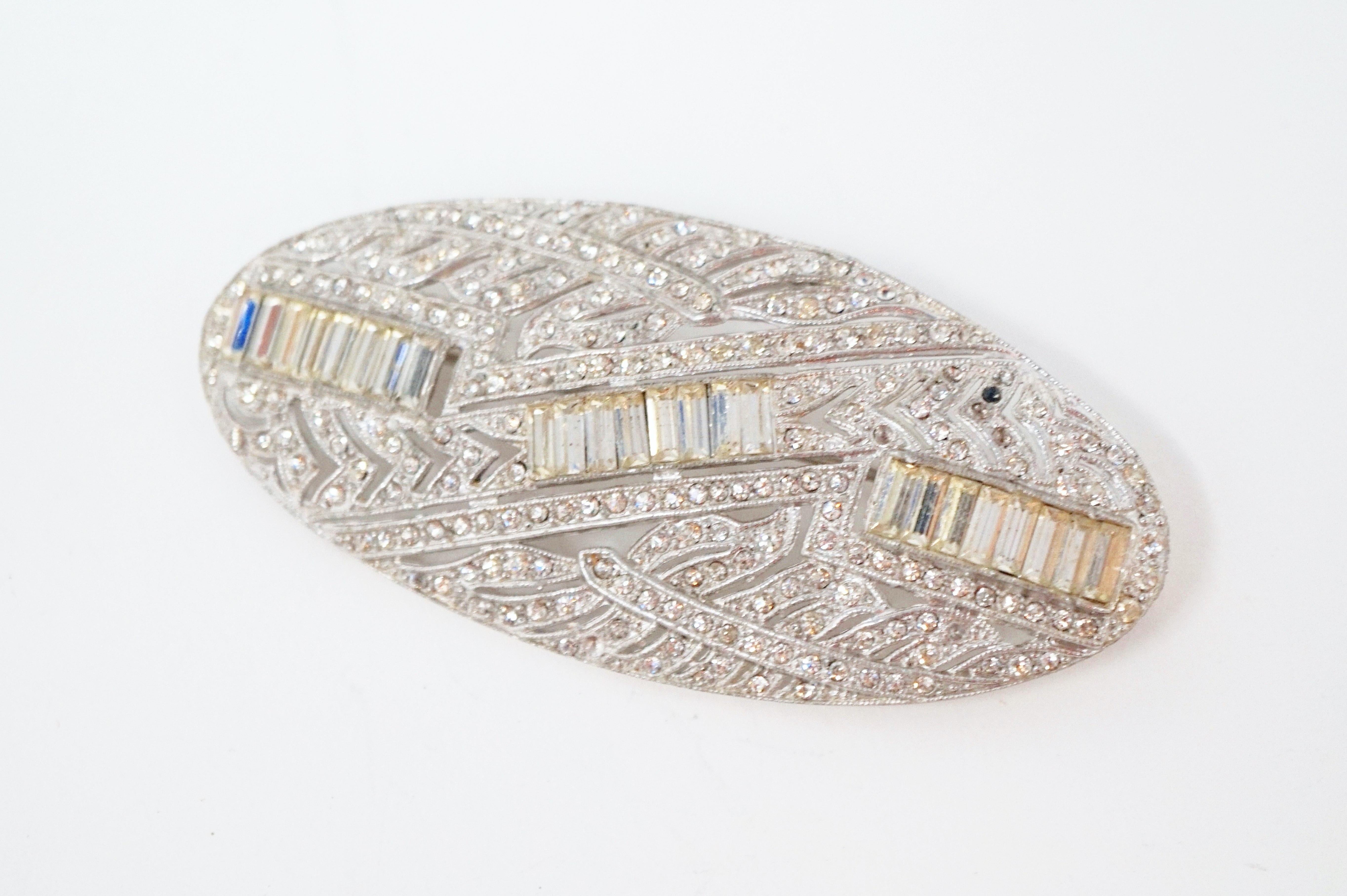 Beautiful vintage art deco style rhinestone brooch, circa mid-20th Century.  This ornate piece features pavé rhinestones and baguette crystal accents nestled in silver tone hardware.  A beautiful piece from a bygone era and a wonderful addition to
