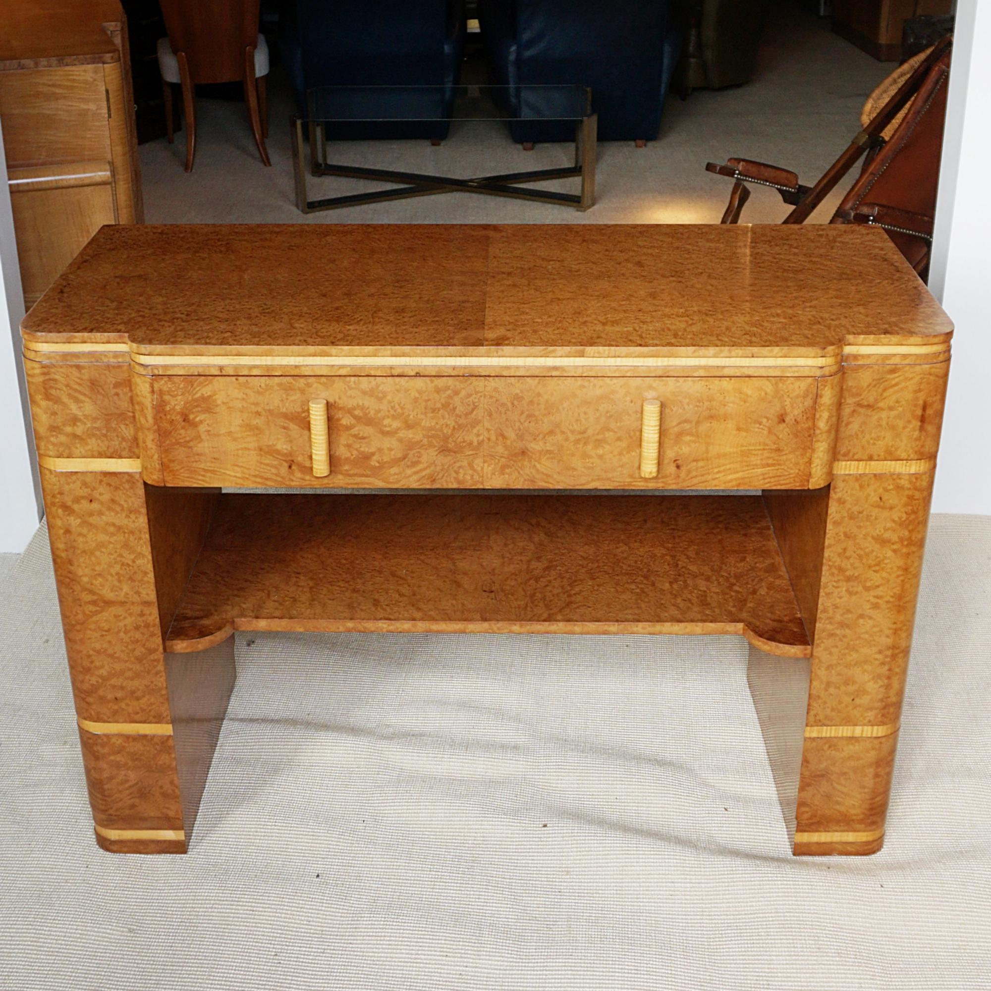An Art Deco Console Table by Harry & Lou Epstein. Burr walnut veneered with satinbirch banding on solid Mahogany. Central upper drawer with a lower inset shelf. Original walnut handles. 

The Epstein company was founded in London during the 1890’s