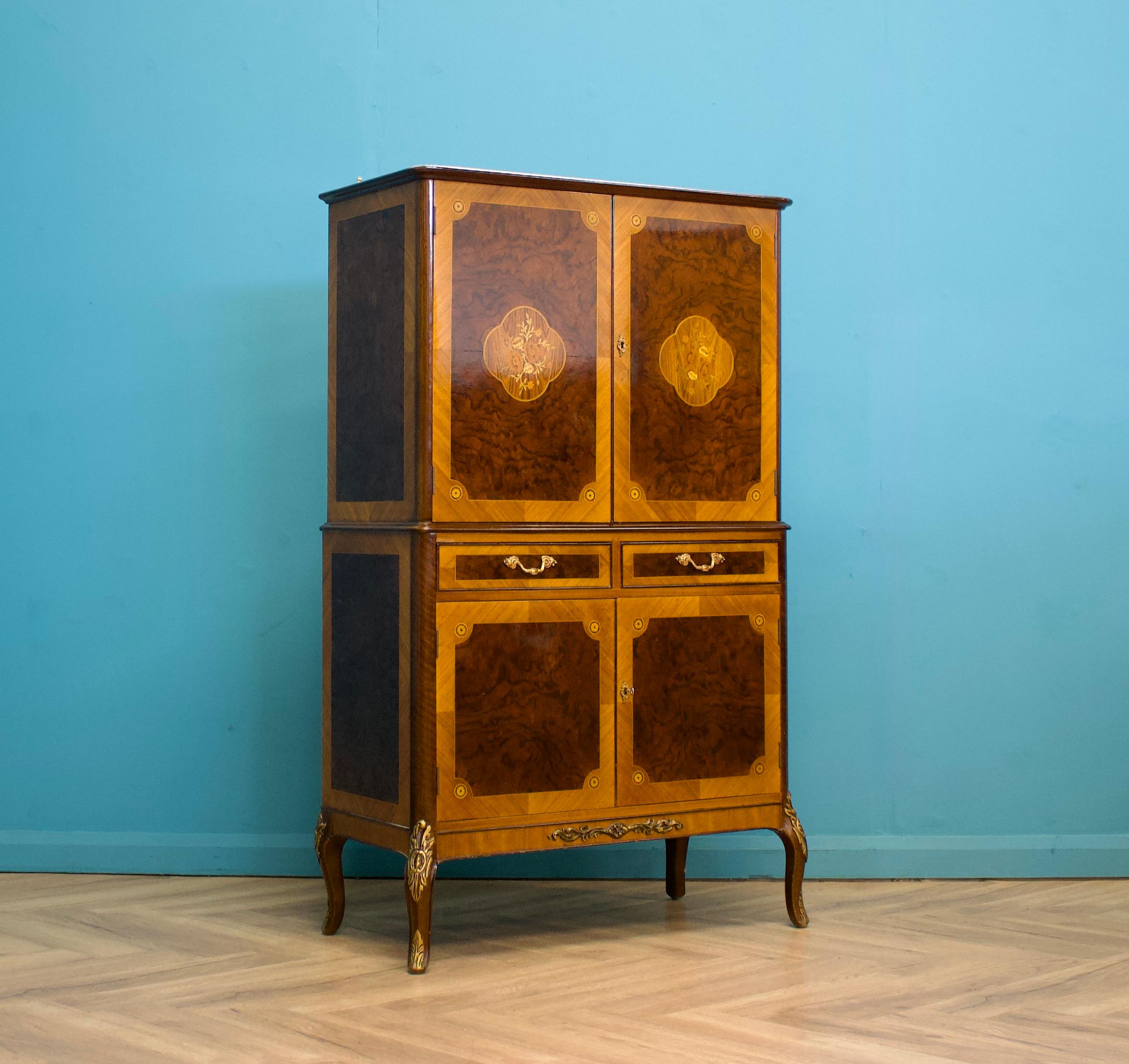 Cette magnifique armoire à boissons ancienne de style français en ronce de noyer, fabriquée par H & L Apstein, présente une marqueterie florale complexe utilisant des placages de bois exotiques sur ses portes.




L'intérieur de l'armoire comporte