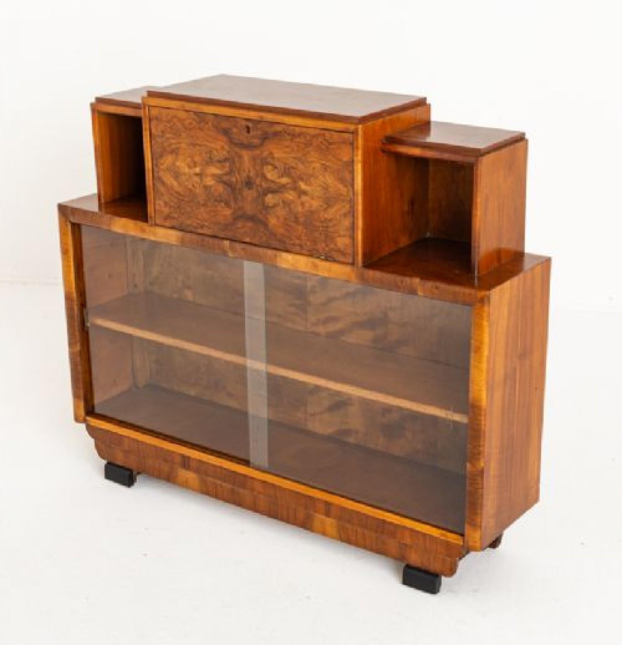 Very stylish art deco walnut bureau cabinet.
Period 1930s
This cabinet stands upon ebonised art deco feet.
The cabinet having 2 glazed sliding doors.
The upper section having a central drop down fall with fitted interior.
The whole of the cabinet