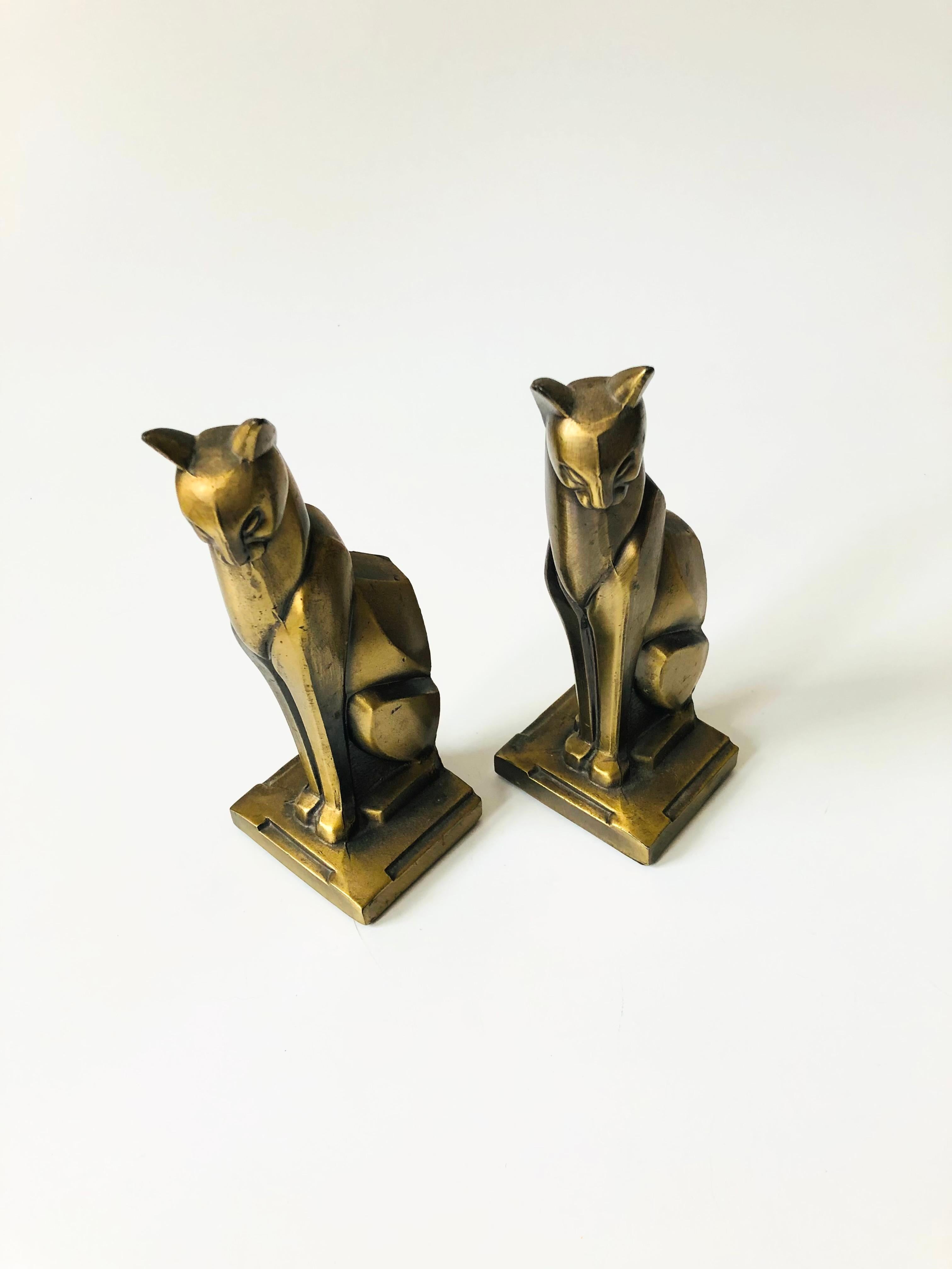 A wonderful pair of vintage Art Deco cat bookends. Made out of cast metal that has been given a gold tone finish. Darkened patina in the crevices. Wonderful angular stylized detailing to the cats. Felted bottoms.
 