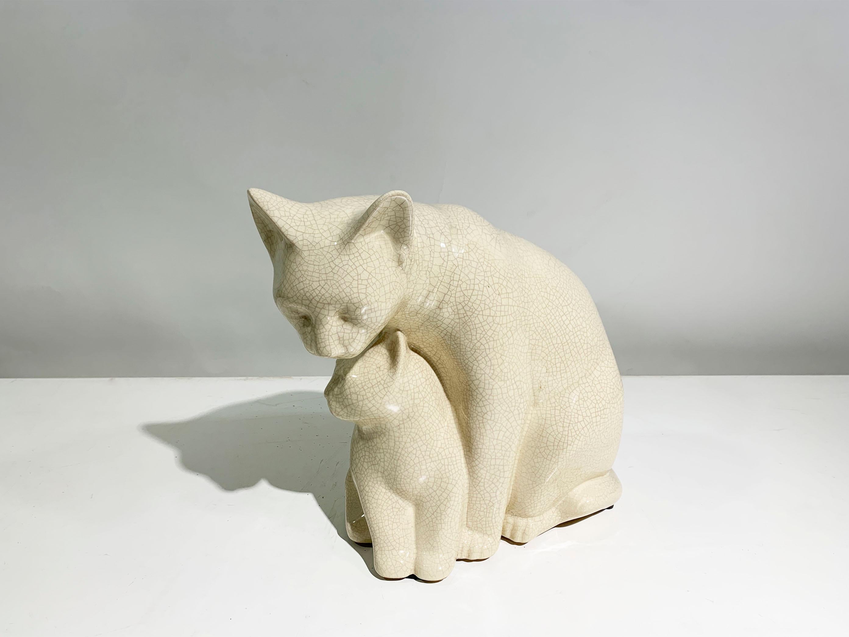 Escultura de gato y su bebé en cerámica blanca esmaltada y craquelada, que representa a una gata madre protegiendo a su bebé, firmada en la parte inferior 
