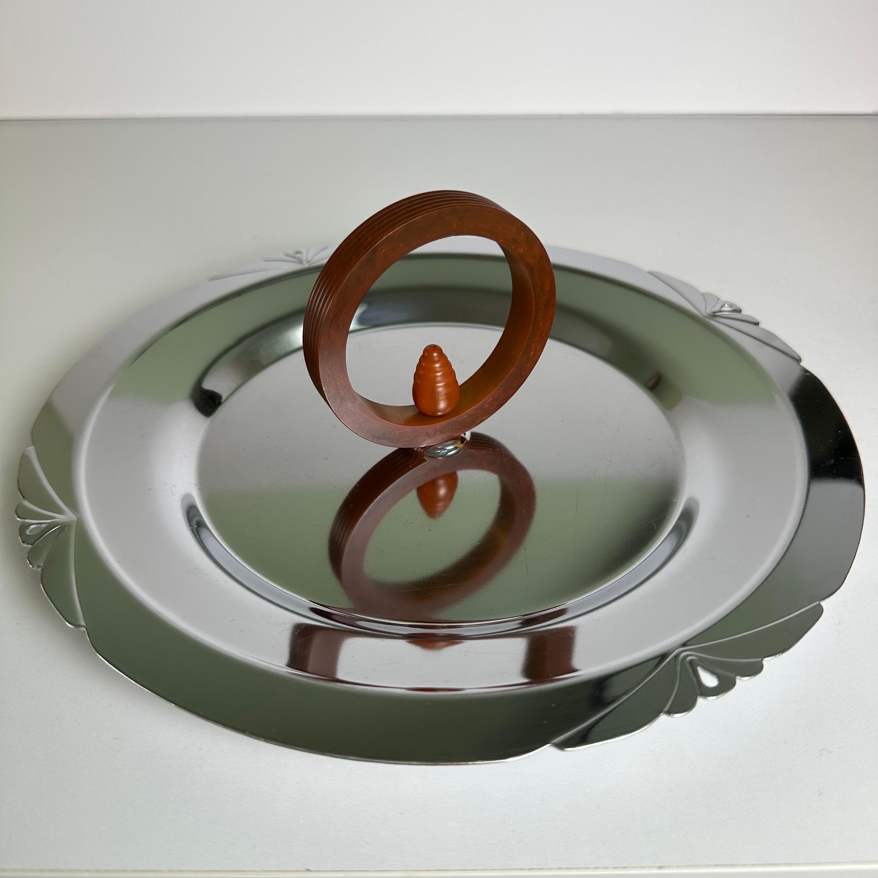 Art Deco chrome plated tray with a Bakelite handle. The round, fluted Bakelite handle is executed in a marbled faux-tortoise or amber color with a beehive or acorn shaped ornament in the middle. Ringed by 4 textured, lotus flower inspired details