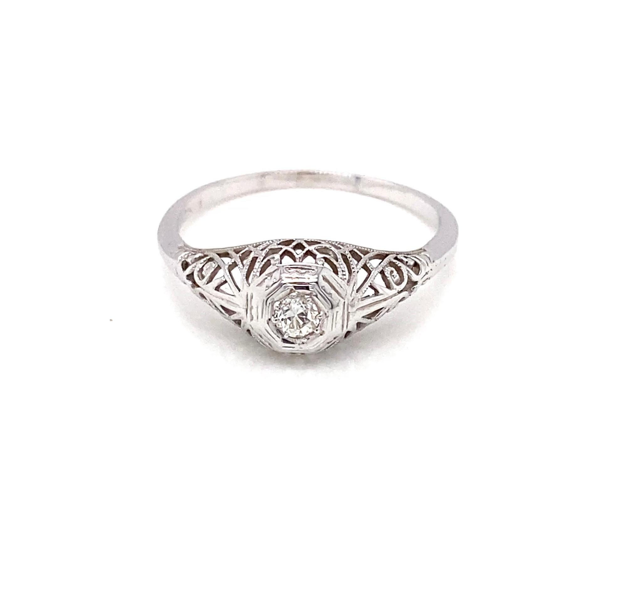 Este anillo Art Déco vintage de oro blanco de 14 quilates presenta en su centro un diamante antiguo de talla europea de aproximadamente 0,14 quilates, de color cálido I - J y claridad VS, que refleja la luz con encanto vintage.  El diamante está