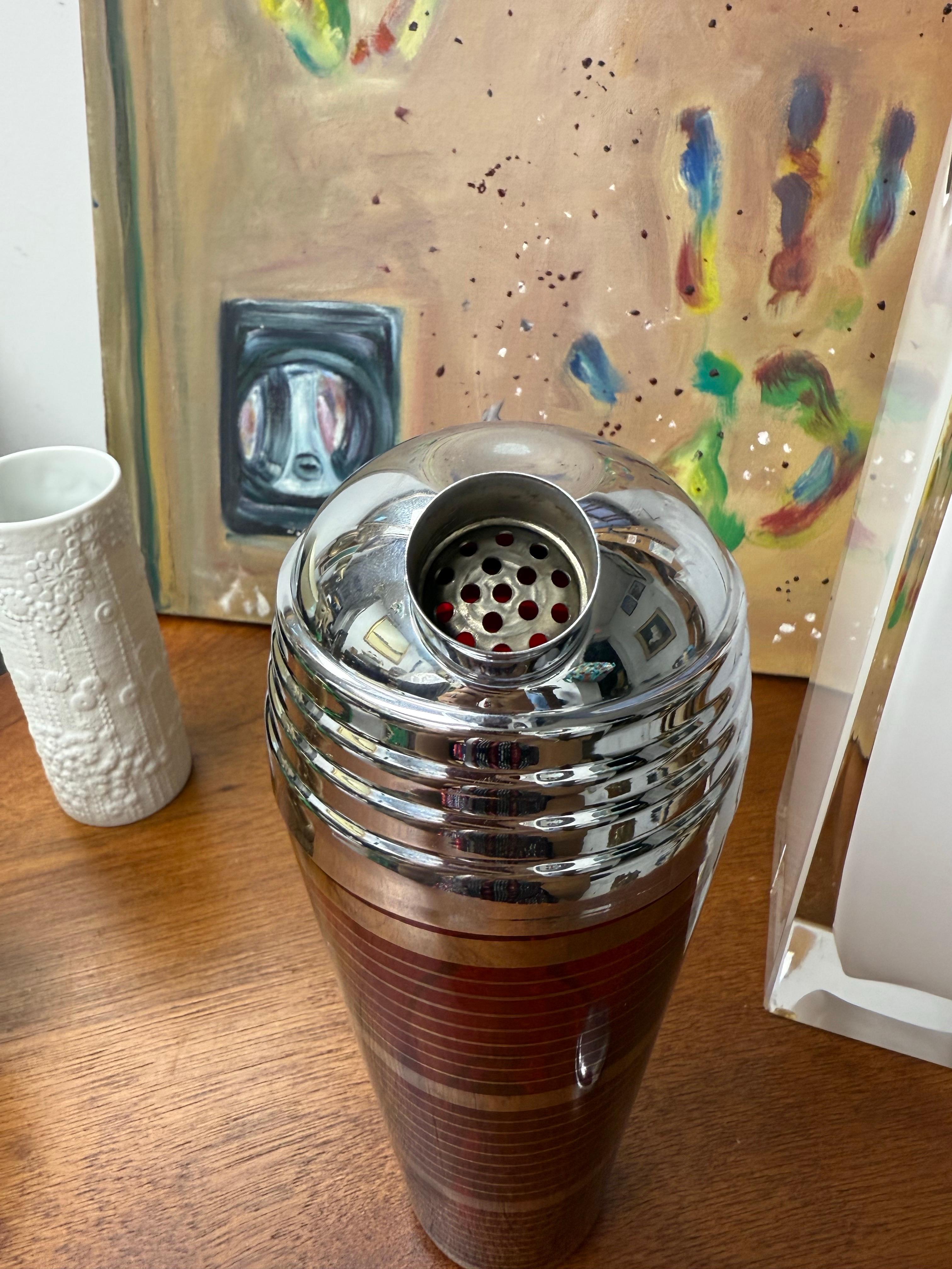 Diese wunderbare  Der rubinrote Art Deco-Cocktailshaker ist mit horizontalen Platinbändern verziert.  Der Shaker aus der Prohibitionszeit hat eine gestufte Chromkuppel.