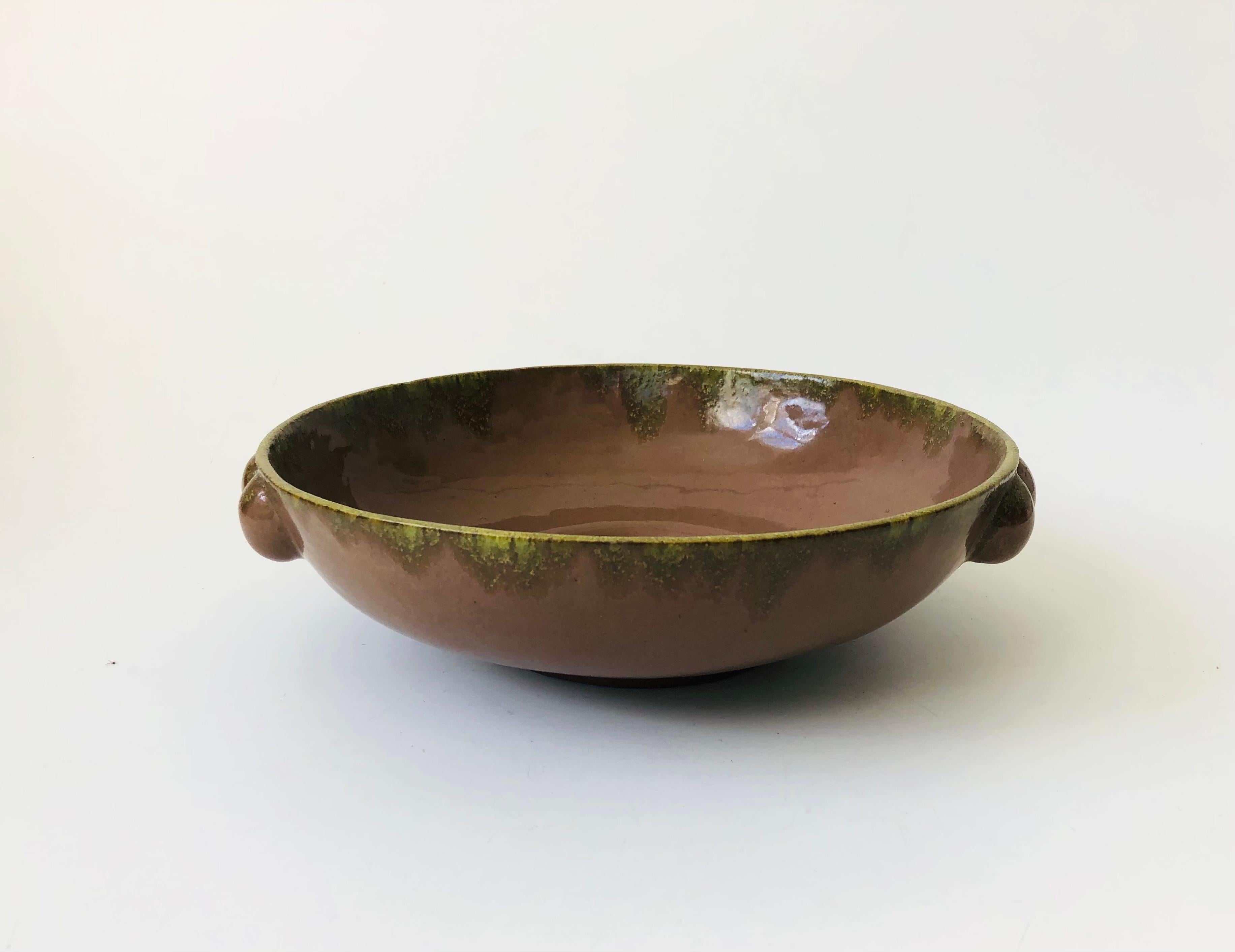 A vintage Art Deco bowl by California ceramicist Cole Merris, circa 1940. Beautiful natural brown glaze with a green glaze accent along the rim. Nice large size for a variety of uses. Round knobs have been formed on 2 sides to create handles. Signed
