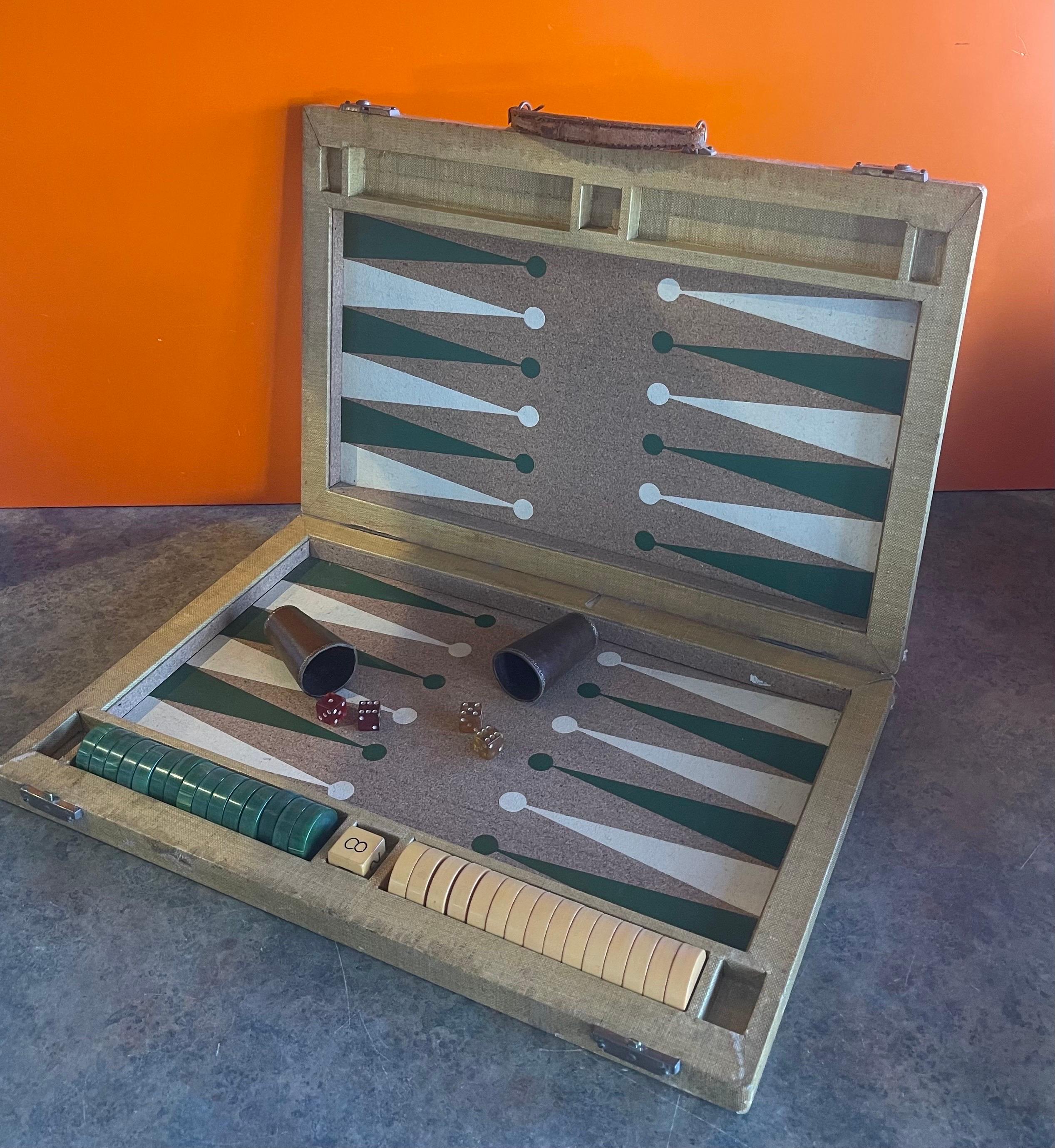 Vintage Art Deco cork and bakelite backgammon set, circa 1940s. Set is complete with a foldable case / board with cork inset, 30 bakelite checkers, doubling, two dice cups and two pair of vintage dice. Overall, the set is in good vintage condition