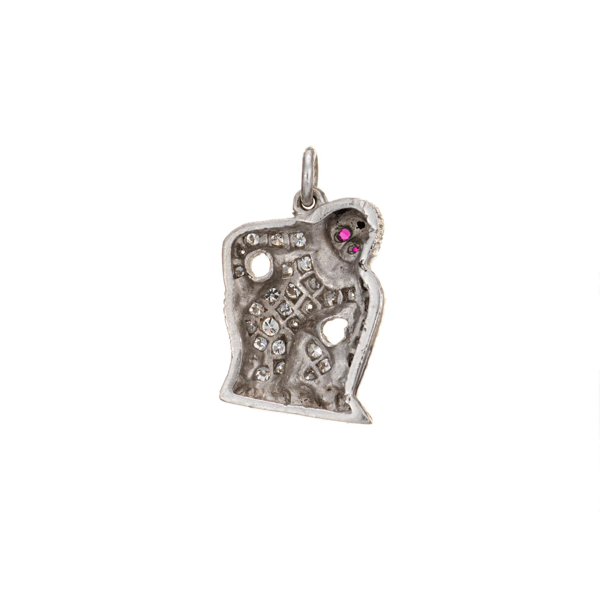 Finely detailed vintage Art Deco era charm crafted in 900 platinum (circa 1920s to 1930s).  

28 round brilliant cut diamonds total an estimated 0.10 carats (estimated at H-I color and VS2-SI1 clarity). Two rubies are set into the eyes (0.01 carat