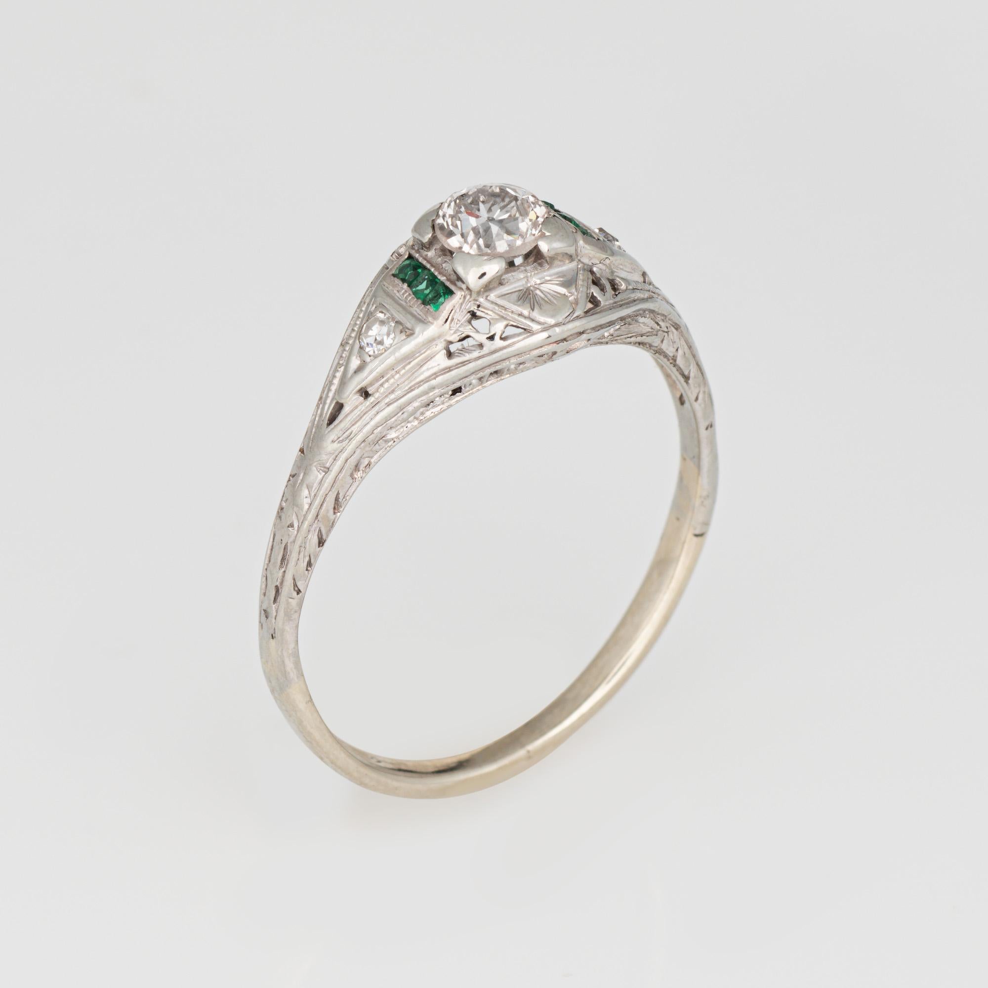Finely detailed vintage Art Deco diamond & emerald ring (circa 1920s to 1930s) crafted in 14k white gold. 

Center set old European cut diamond is estimated at 0.20 carats, accented small approx. 1.5mm French cut emeralds. The diamond is estimated