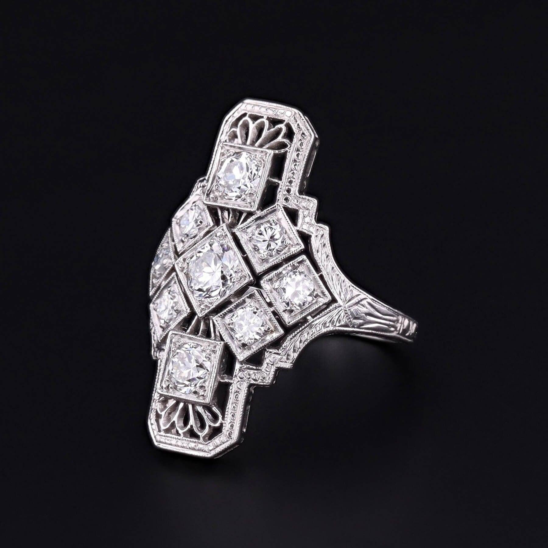 Questo scintillante anello dell'epoca Art Deco degli anni '20 presenta 9 diamanti in una montatura in filigrana di platino.

Il moderno diamante rotondo brillante centrale pesa circa 0,25 carati con purezza VS1-VS2 e colore F-G, mentre gli otto
