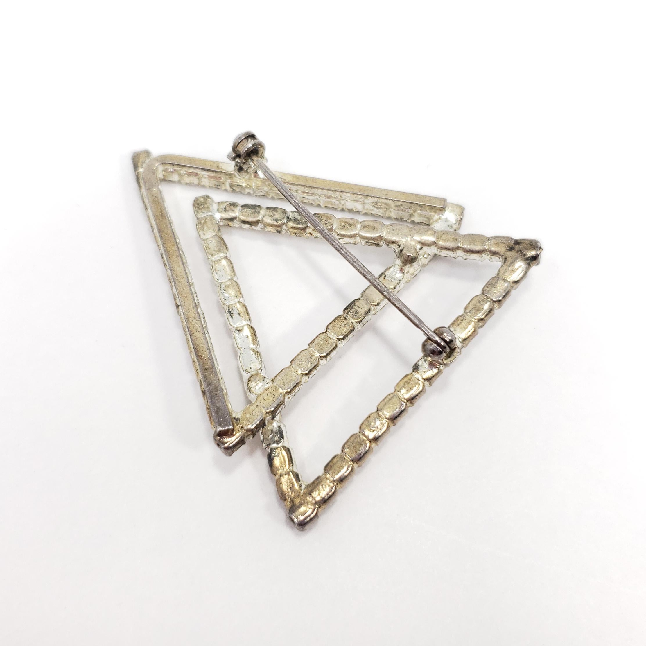 This delightful Art Deco brooch features to interlocked triangles, with sparkling clear crystals. Set in a silver-tone setting.
