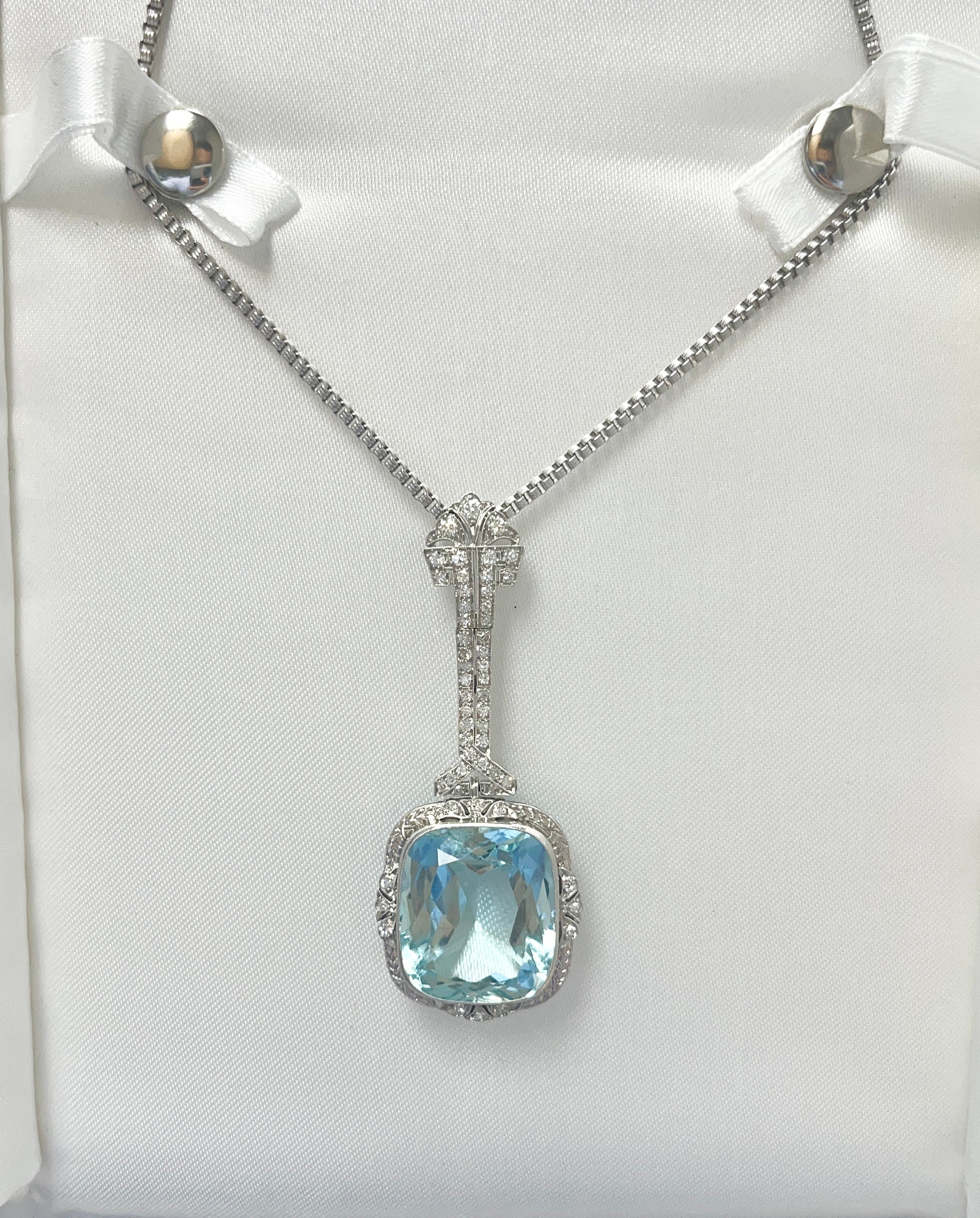 GIA-certified Art Deco Aquamarine Necklace, a mesmerizing blend of intricate filigree platinum setting, old euro cut diamonds, and a massive cushion cut aquamarine. This sophisticated piece balances subtle details with a vibrant blue center stone,