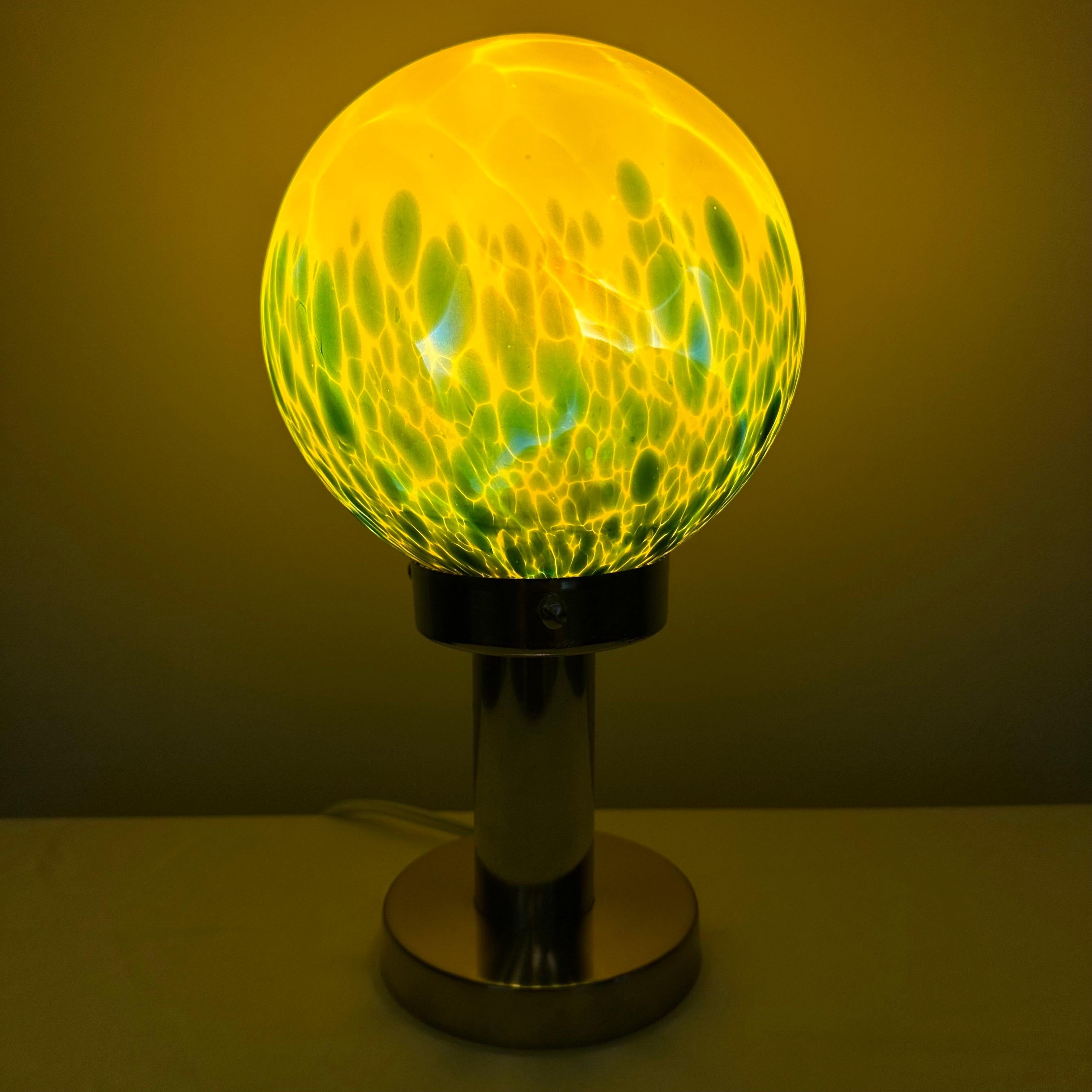 Amazing vintage Art Deco table lamp with a large, bright and colorful glass globe. A chunky, tubular column form chrome plated base supports a one of a kind round globe. A bright neon yellow color at the top, mixes and swirls with darker blue below,