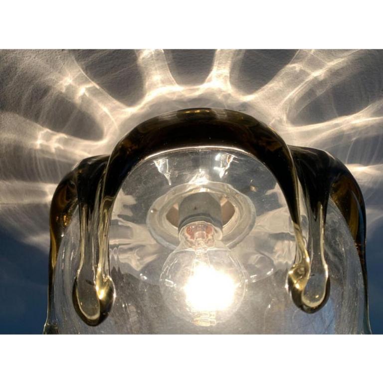 Imponente lampada da soffitto o da parete in vetro.

Il cappuccio della lampada è in vetro trasparente. Il bordo è decorato con vetro verde, che avanza a intervalli regolari nelle dita. Il sorprendente corpo luminoso crea un impressionante gioco di